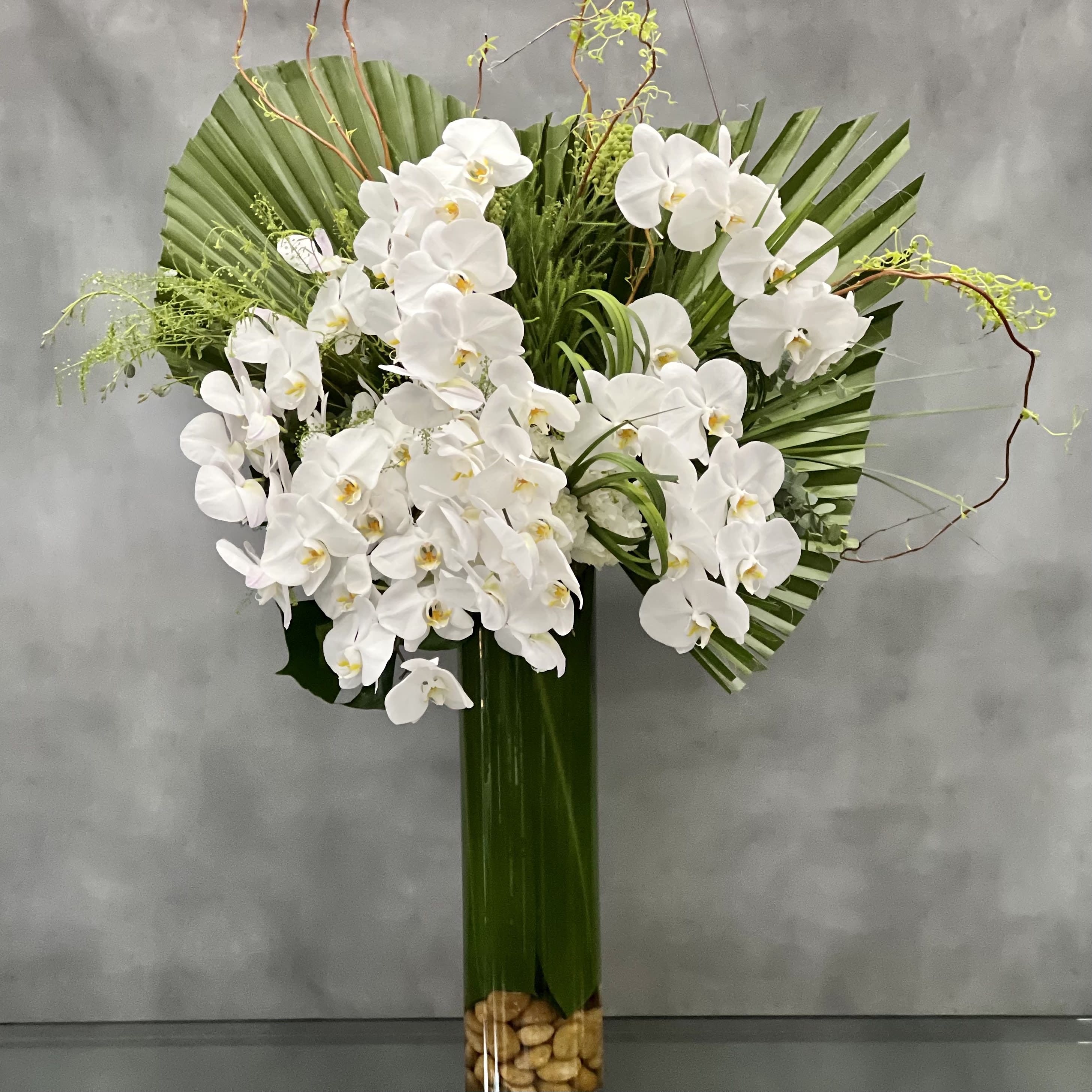 Touch the Sky - Sherman Oaks Florist - Simple and elegant... lovely white Orchids stand tall in this slender cylinder class vase, accented with twisted branches that rise above and a cluster of pale green hydrangeas that add a decorative touch at its base.  