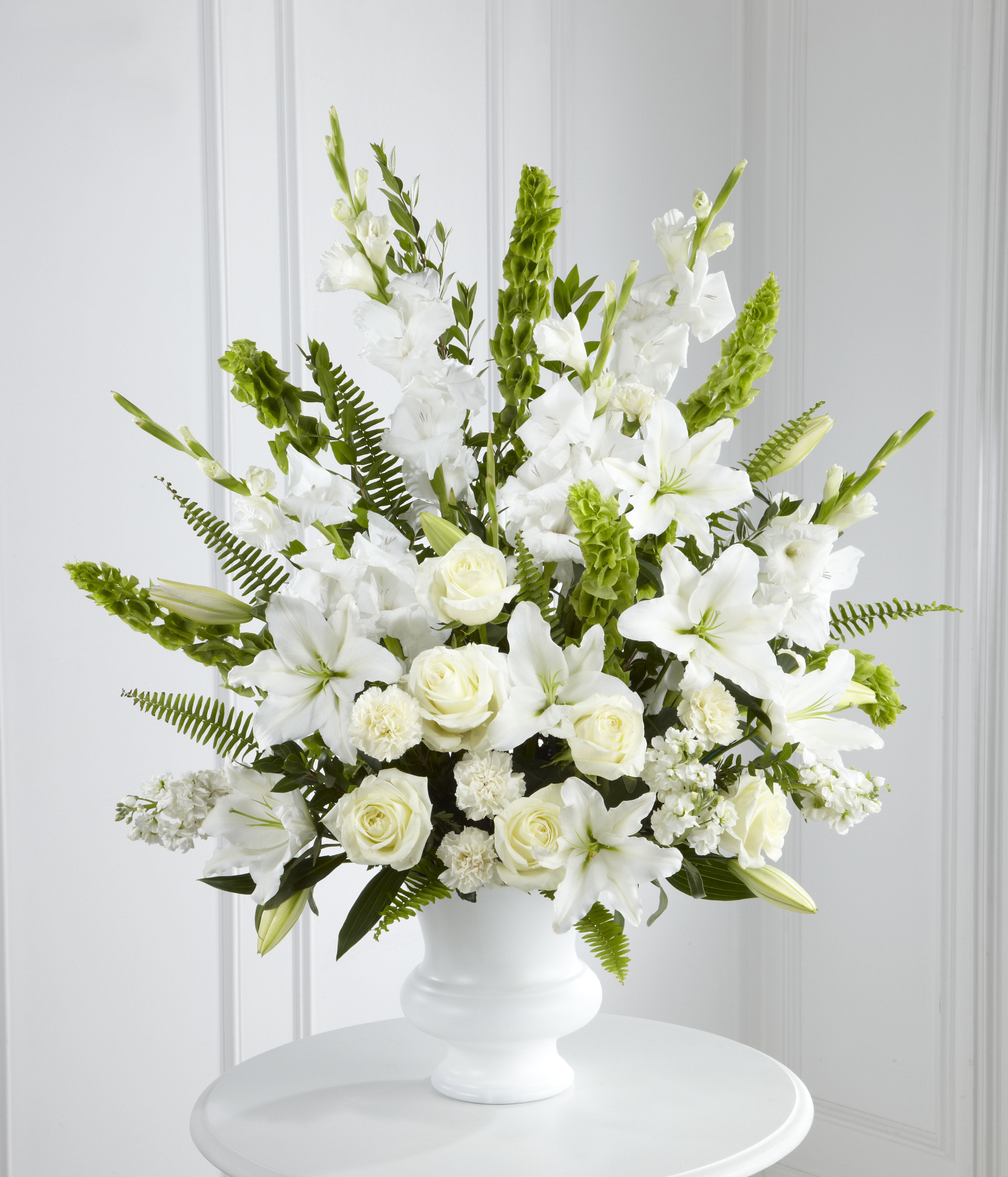 White floral arrangement in a white vase with roses and lilies