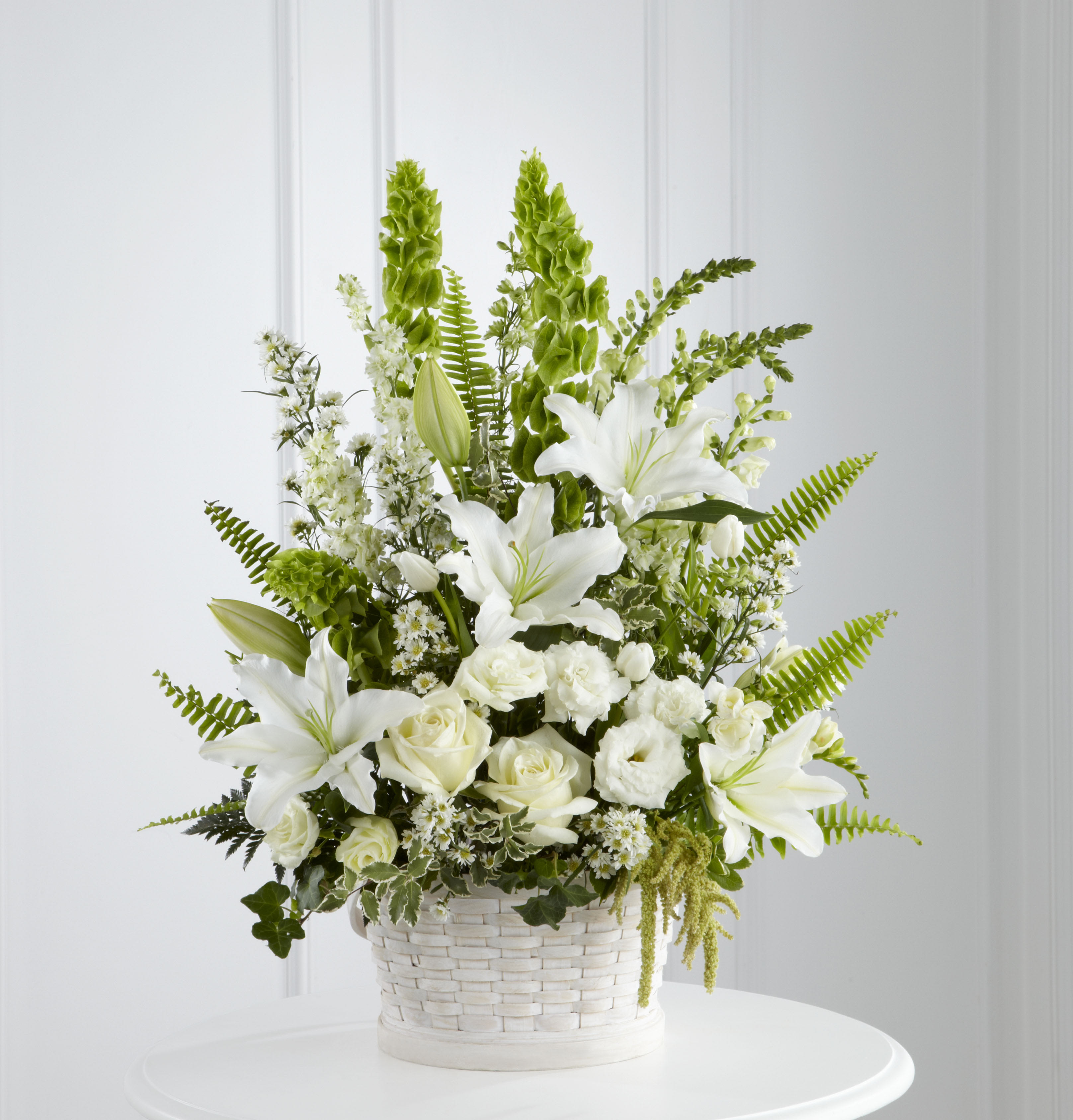 White lilies and roses arranged in a white basket