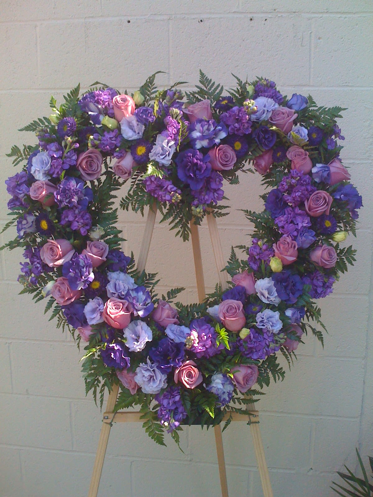 Heart-shaped floral wreath with pink and purple flowers on an easel