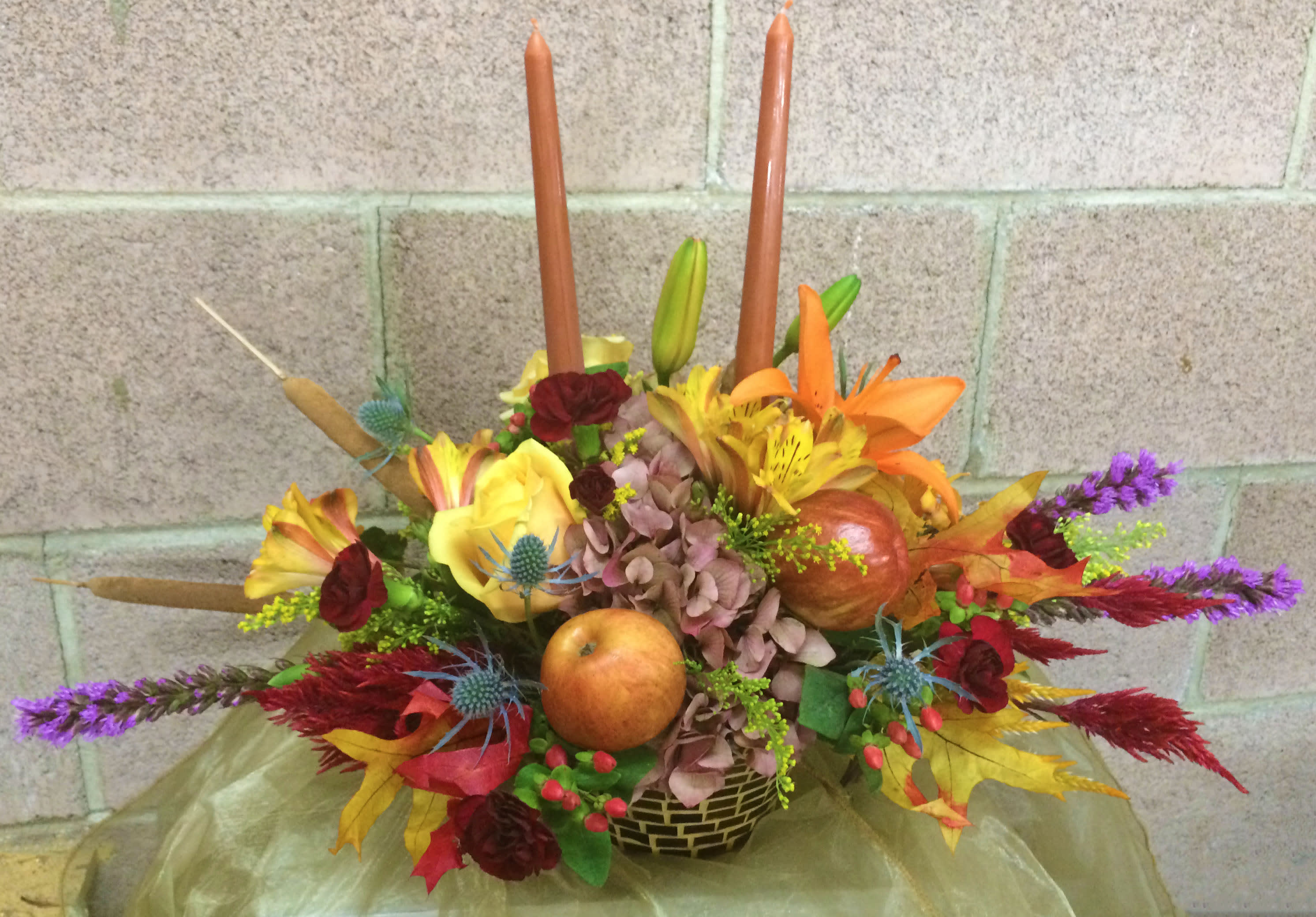 Autumn floral centerpiece with candles and fruit in a low basket