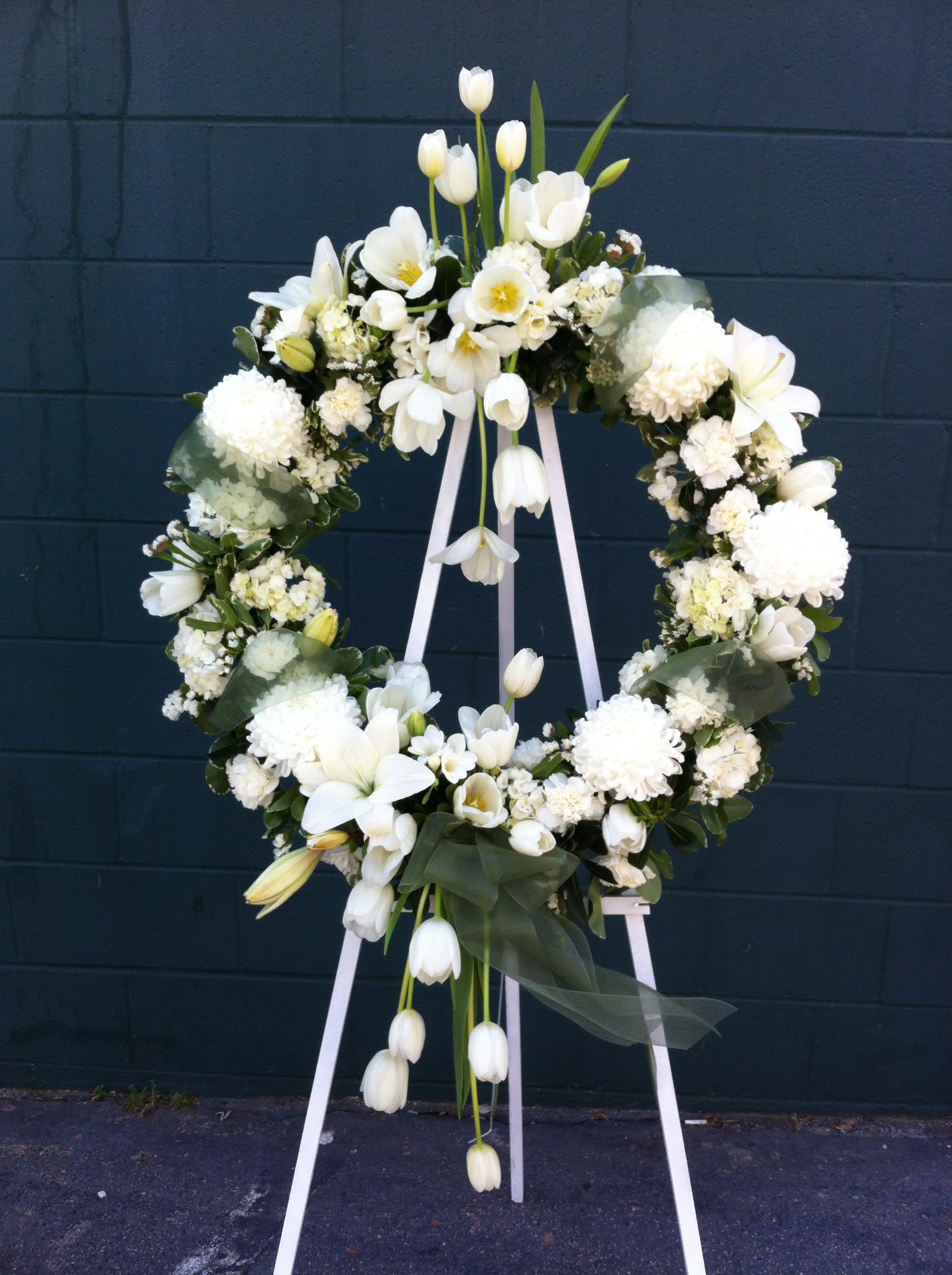 White floral wreath on a standing easel with trailing tulips