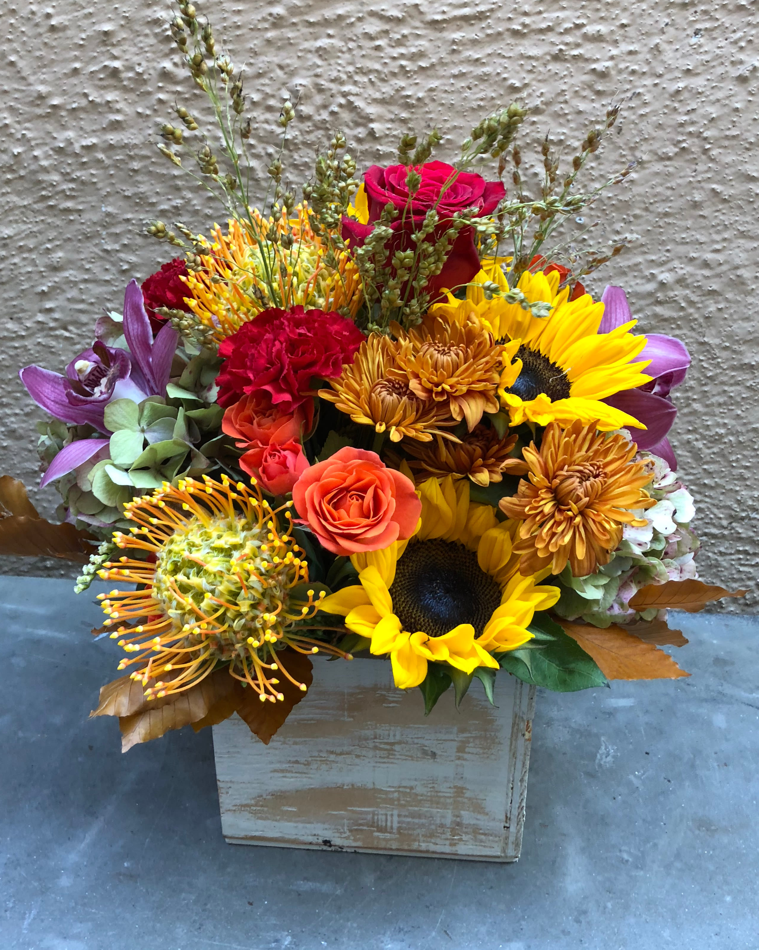 Mixed bouquet with sunflowers, roses, and chrysanthemums in a wooden box