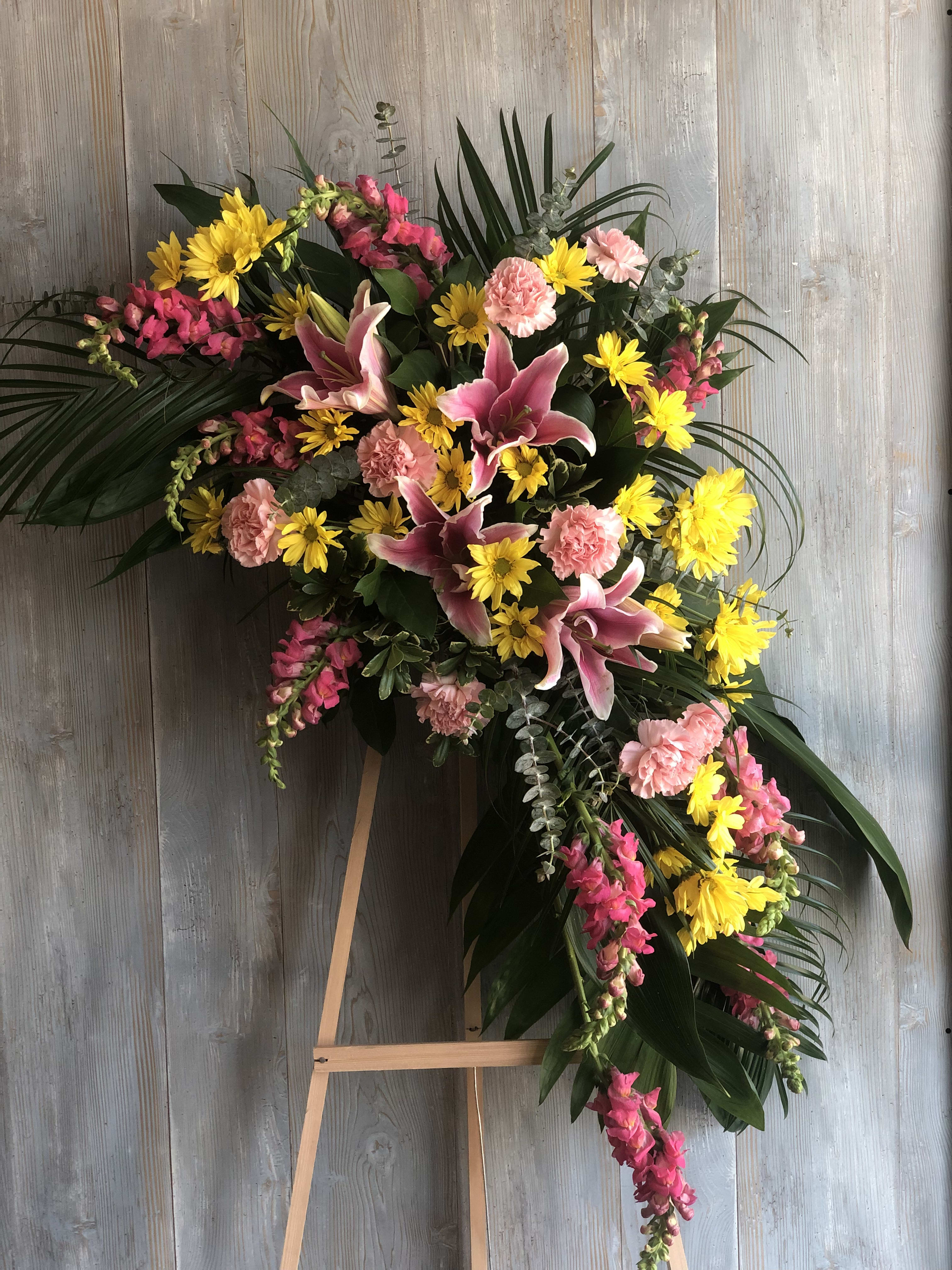 Standing floral spray with pink lilies, yellow daisies, and carnations