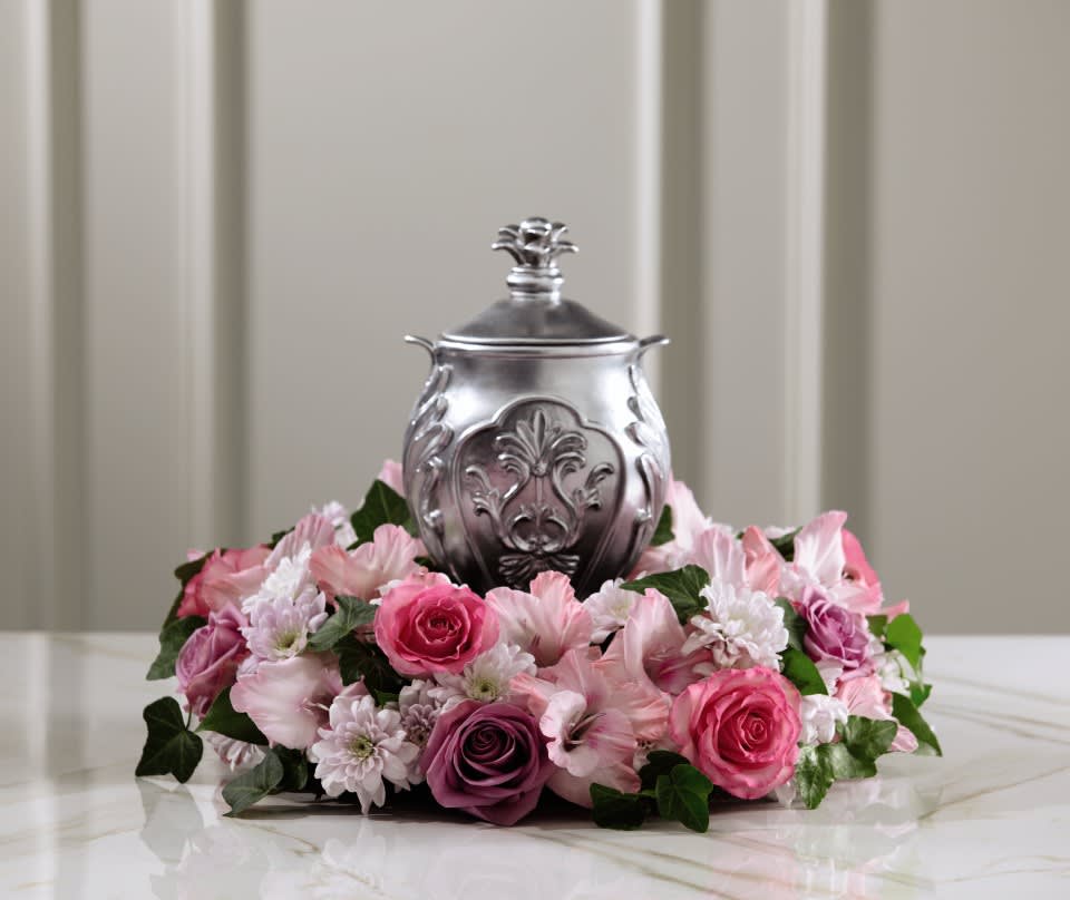 Pink floral arrangement around a silver urn