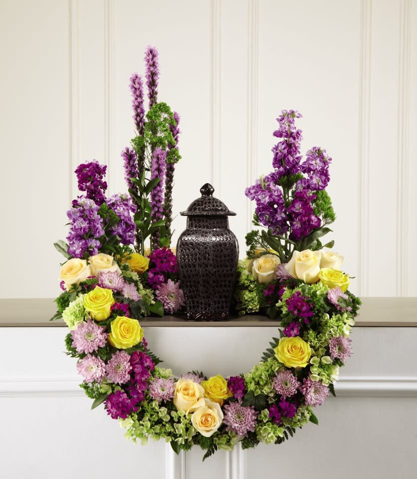 Purple and yellow floral wreath around a black urn