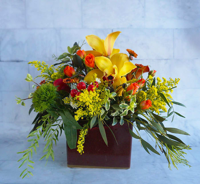 Yellow lilies and orange roses in a burgundy vase