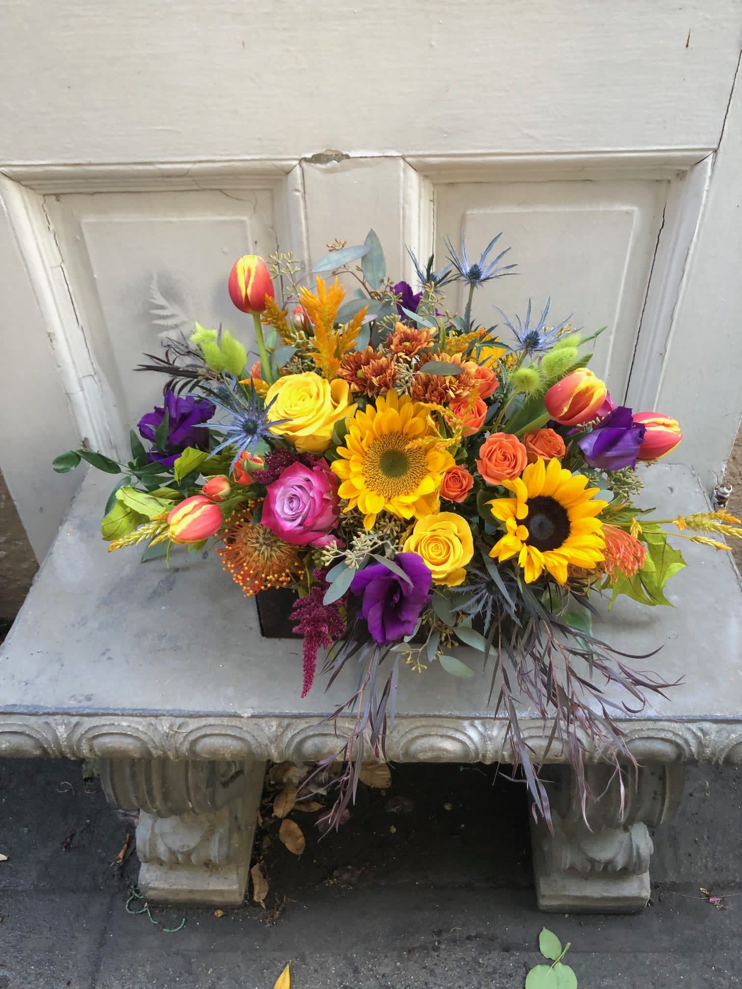 Colorful mixed bouquet with sunflowers, roses, and tulips in a black container