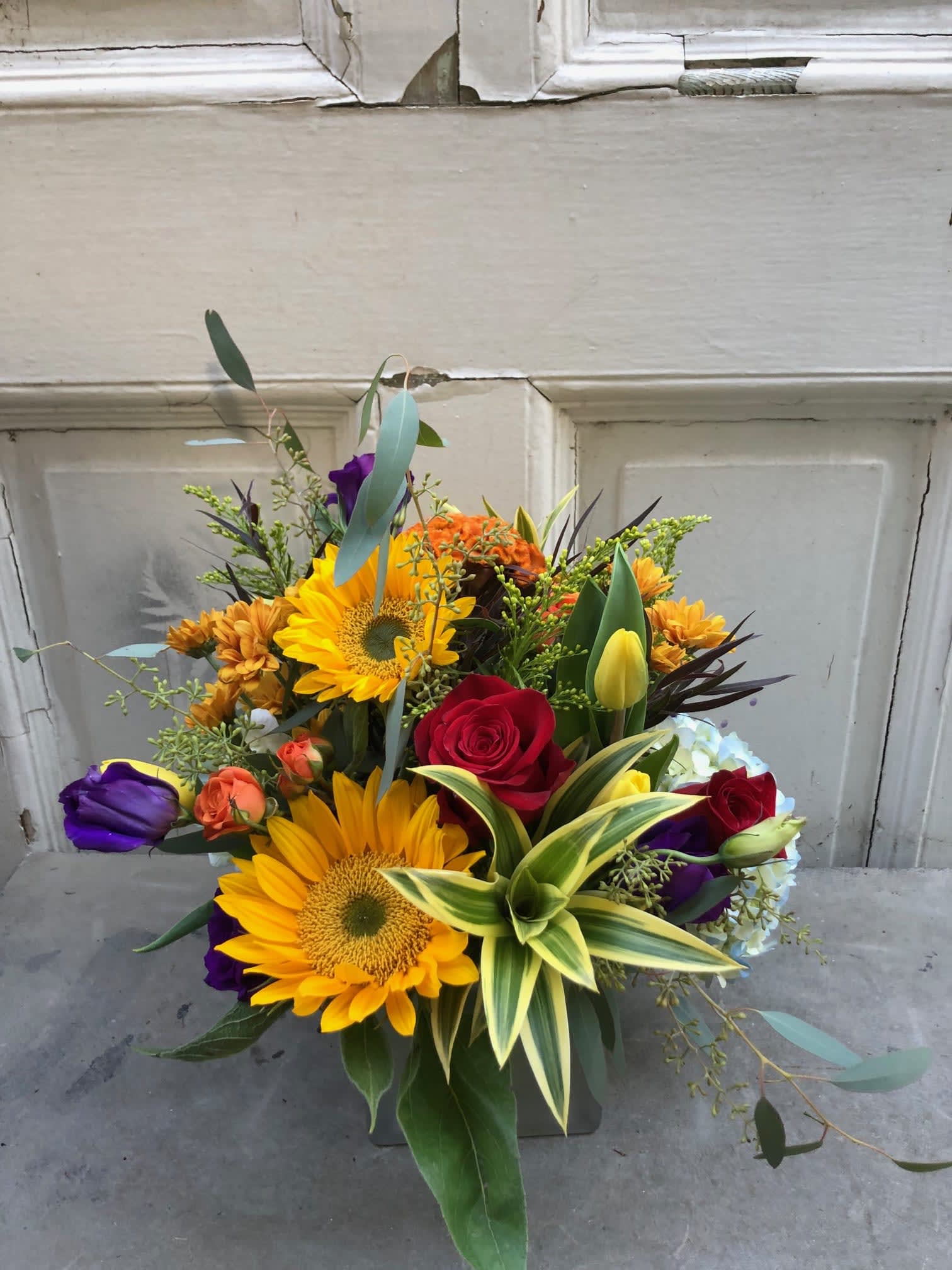 Mixed bouquet with sunflowers, roses, and tulips in a vase