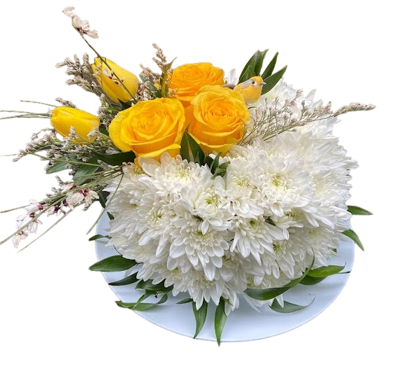 Low arrangement of yellow roses and tulips with white mums on a white plate