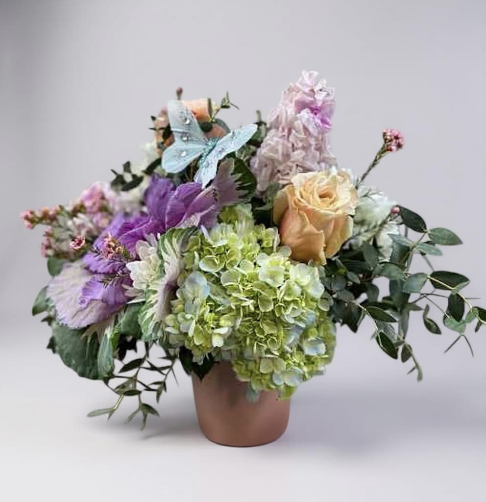 Bouquet of pastel flowers in a terracotta vase with a butterfly decoration