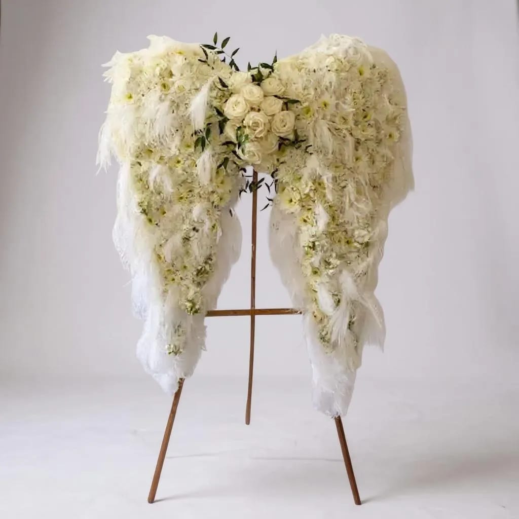 White floral funeral spray on a wooden stand