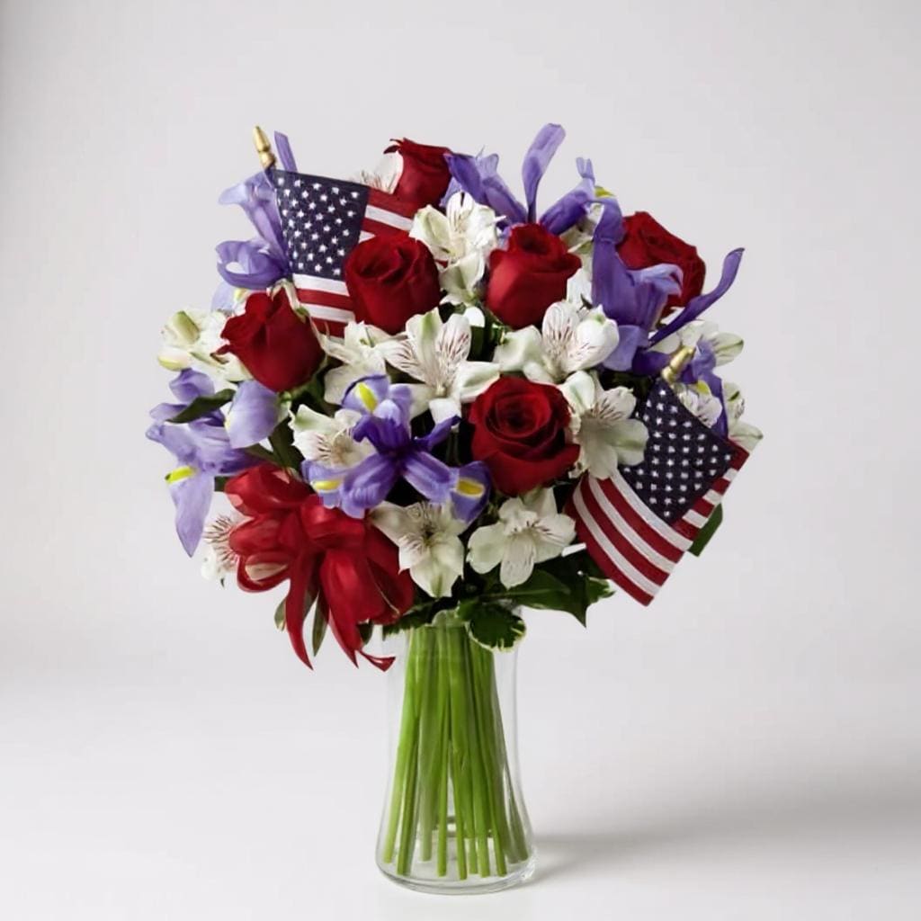 Bouquet of red roses and white flowers with small American flags in a glass vase