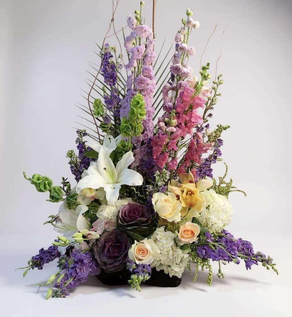 Tall mixed floral arrangement with lilies, roses, and purple blooms