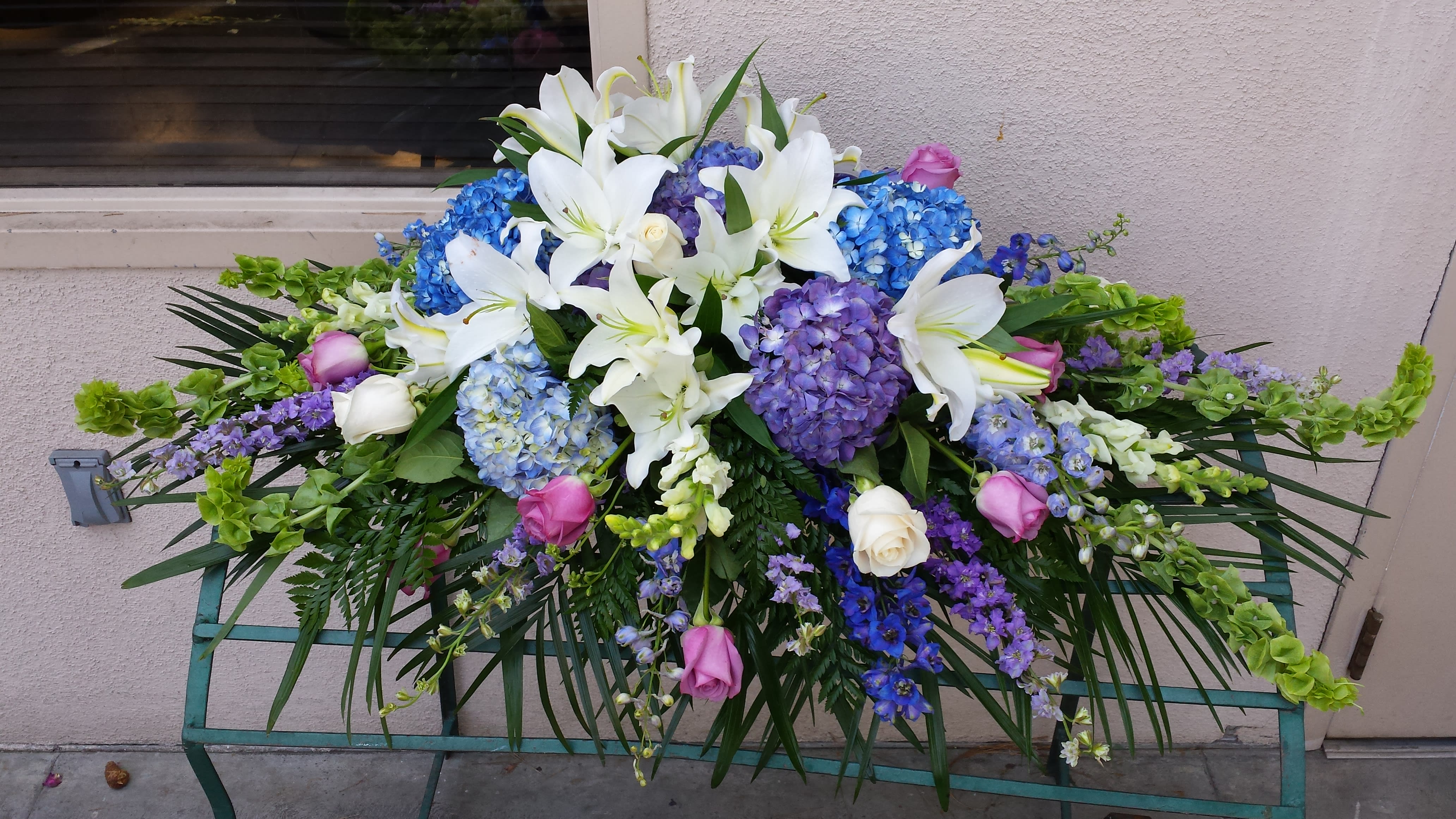 Large floral spray with white lilies, blue hydrangeas, and pink roses