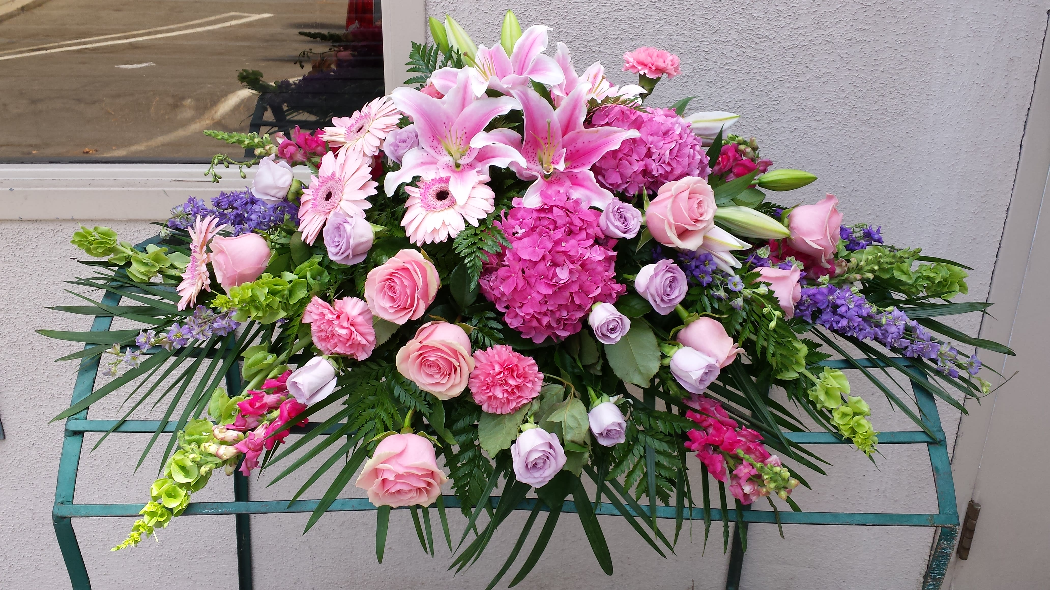 Large pink and purple floral arrangement with lilies, roses, and hydrangeas