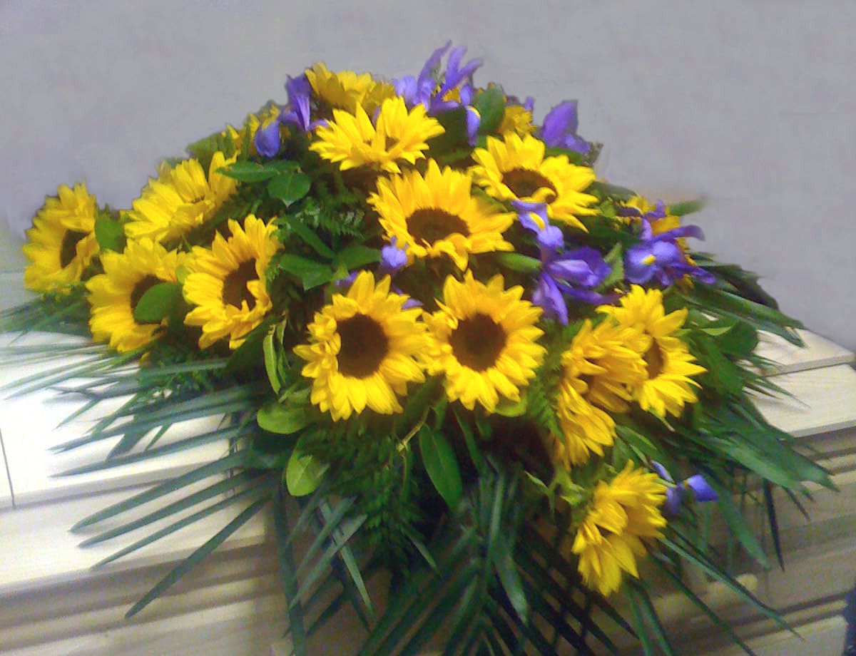 Yellow sunflowers and purple flowers arranged in a low spray