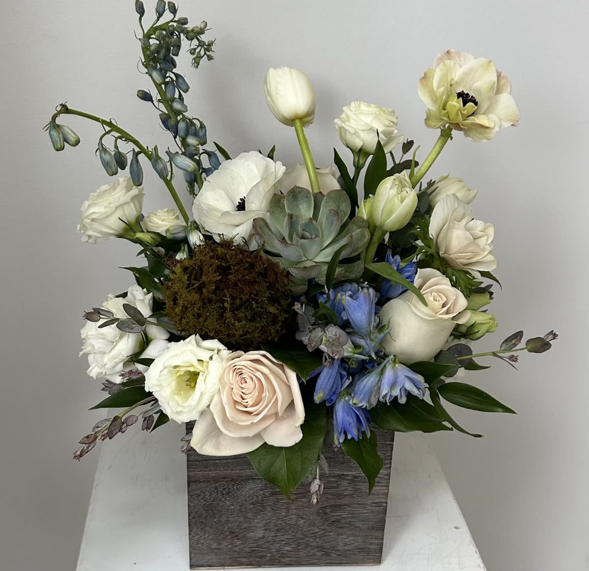 White and pale pink flowers in a wooden box with blue accents and a succulent