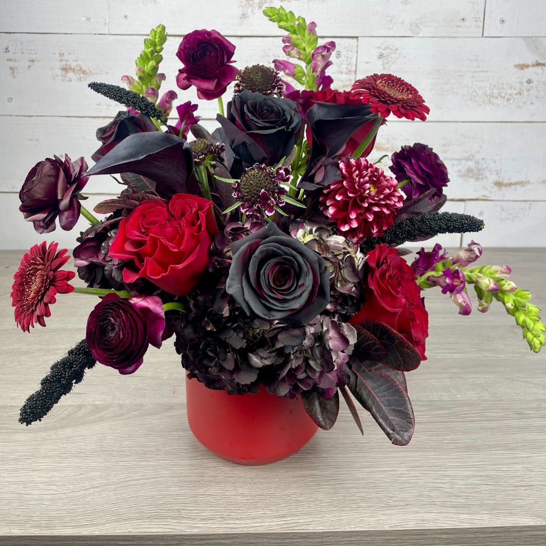Bouquet of red, black, and purple flowers in a red vase