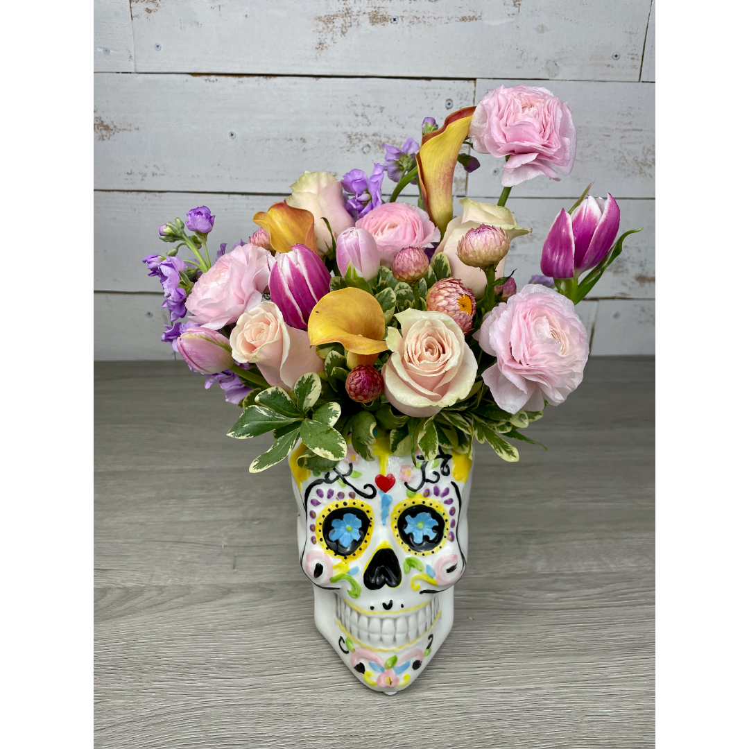Pink and purple flowers arranged in a painted skull vase
