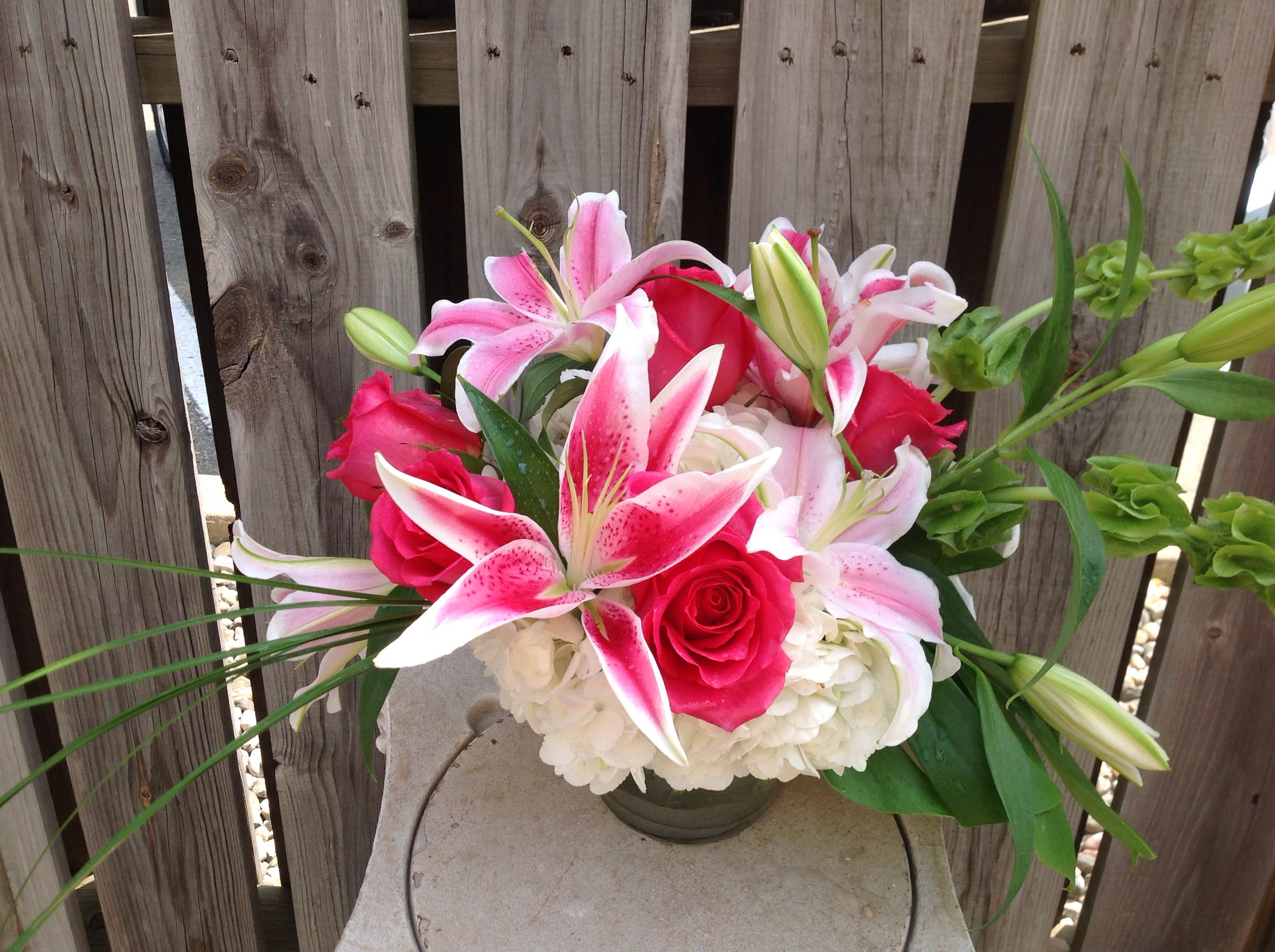 Pink lilies and roses arranged in a low vase