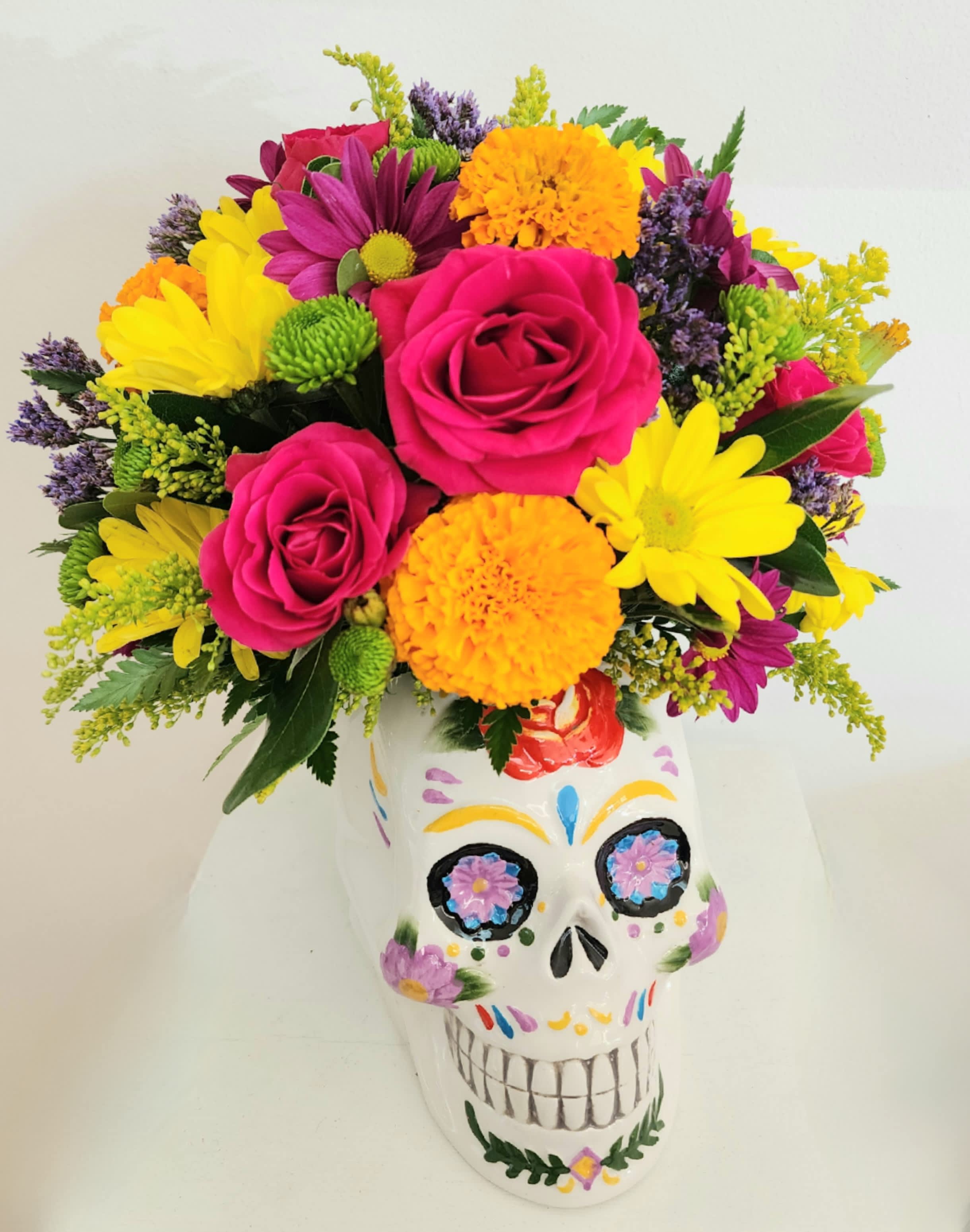 Colorful bouquet of roses and daisies in a painted skull vase