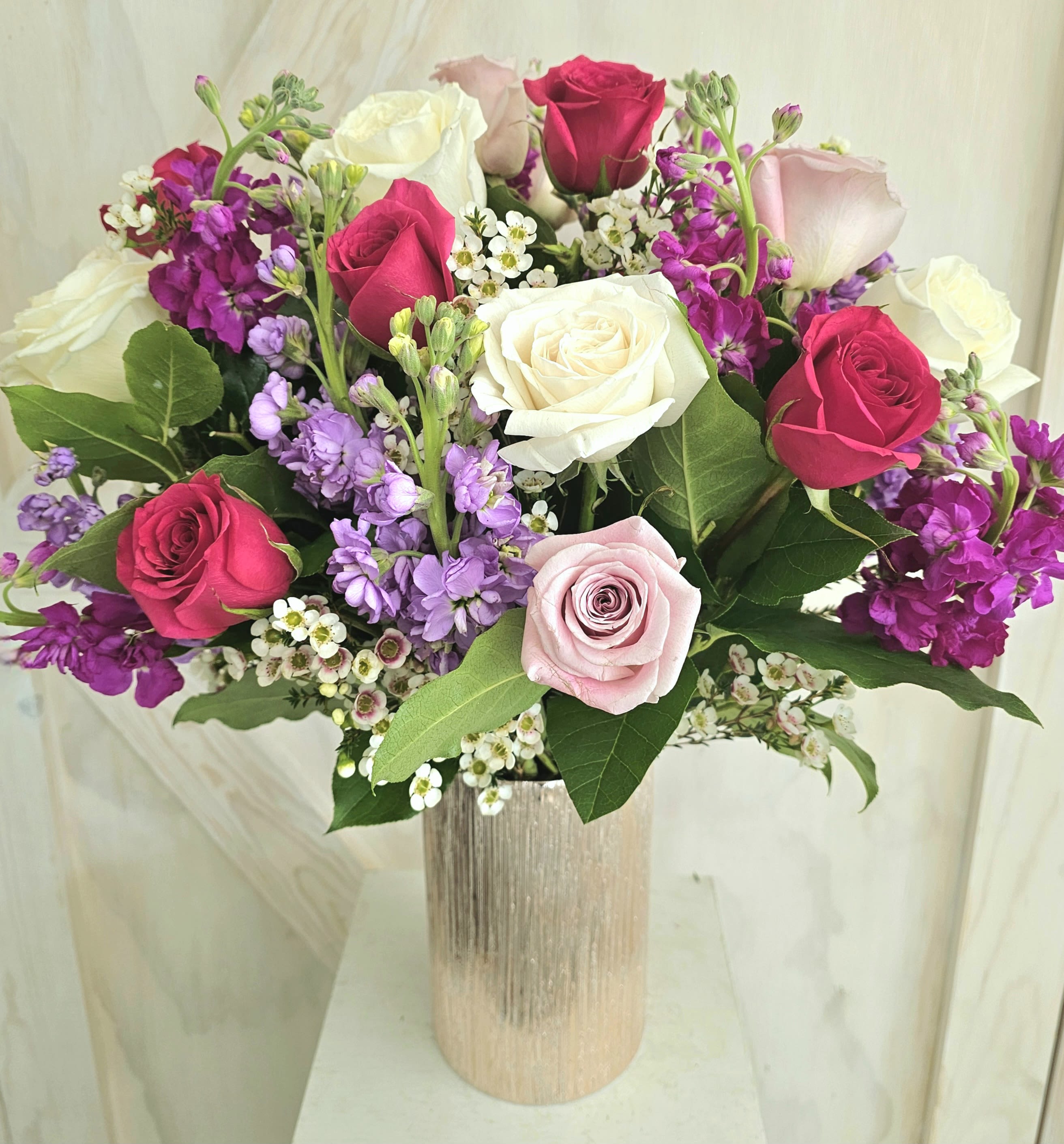Bouquet of pink, white, and purple roses in a tall vase