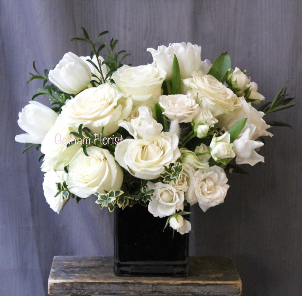 White roses and tulips arranged in a black square vase