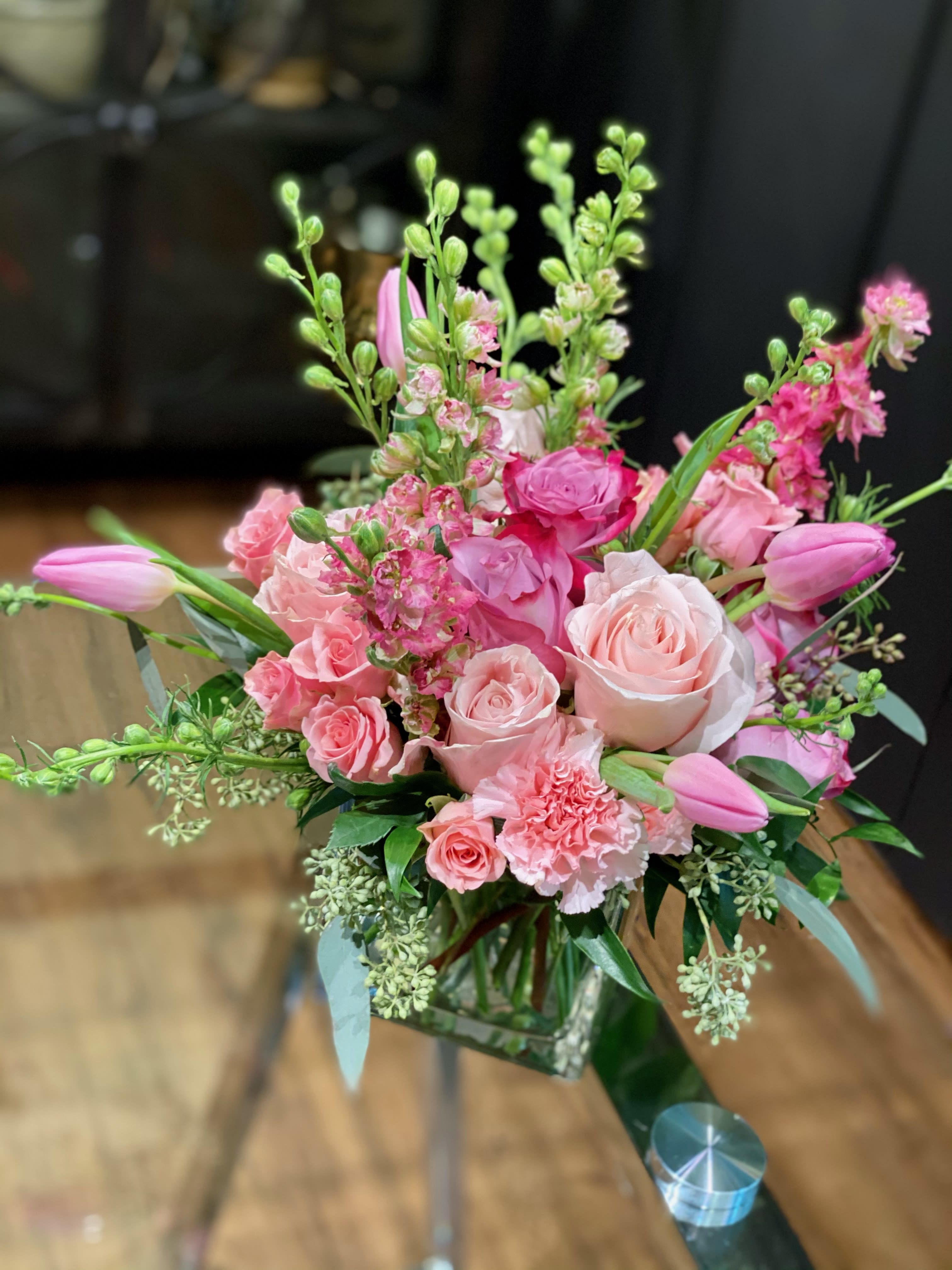 Pink roses and tulips arranged in a clear glass vase