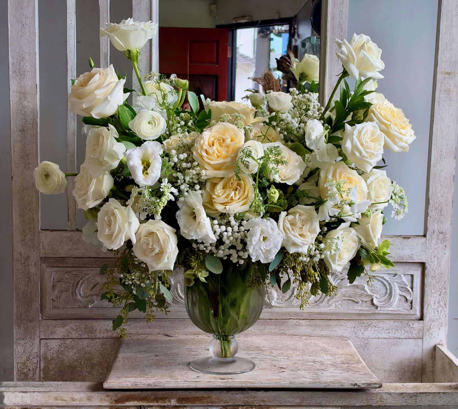 White rose arrangement in a green glass vase