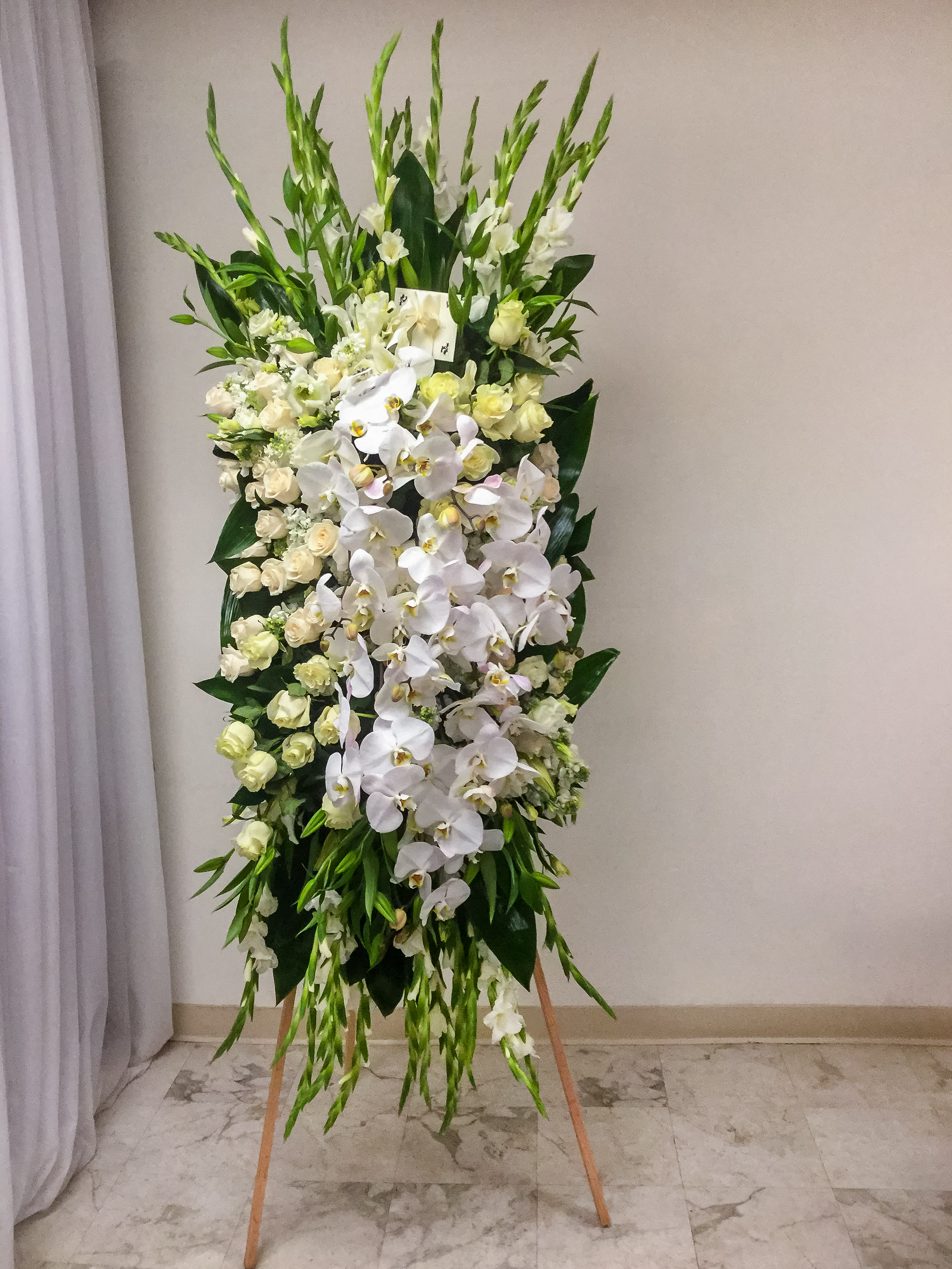 Tall standing floral spray with white orchids and cream roses