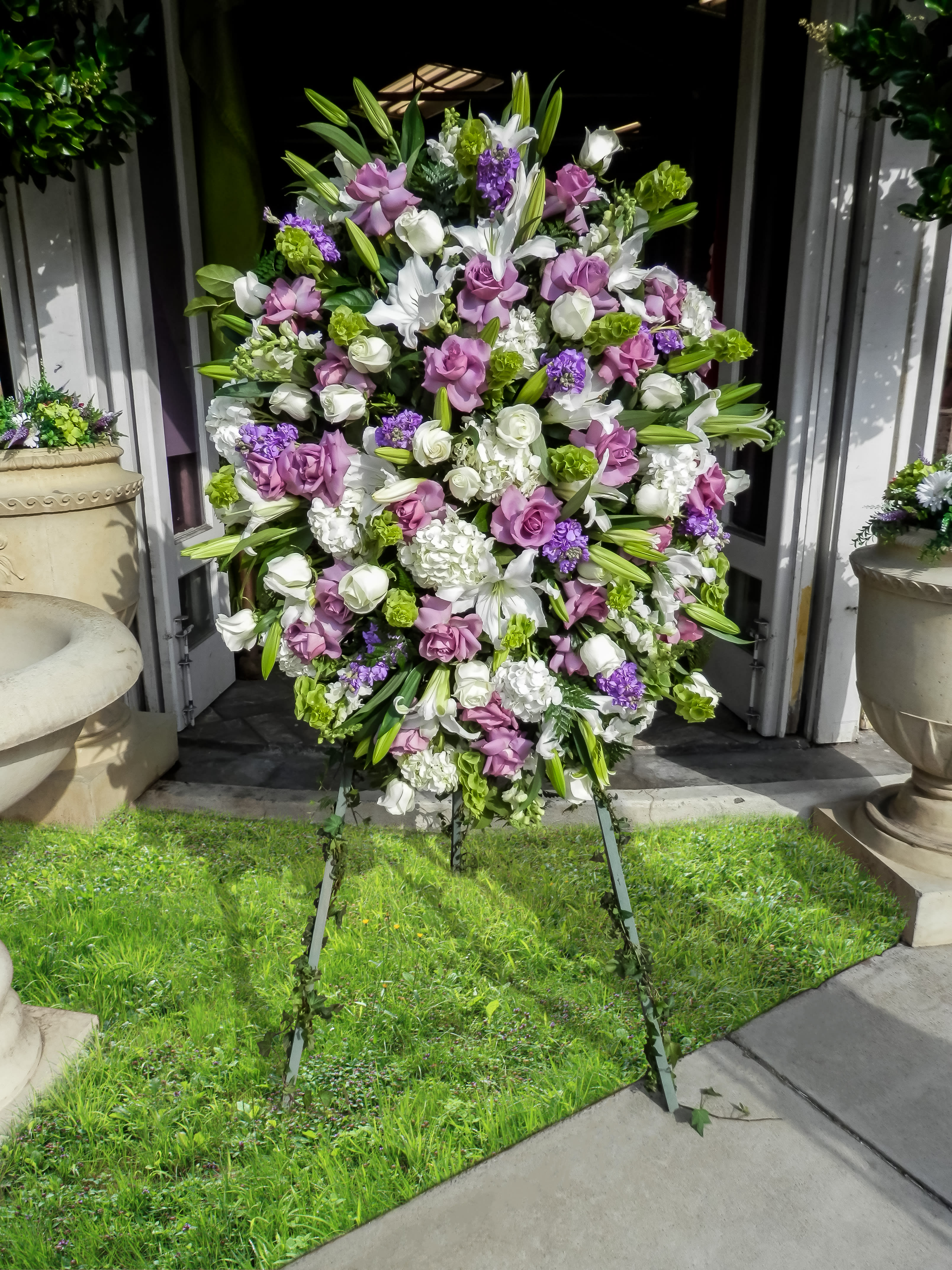 Large standing floral spray with white, lavender, and green blooms