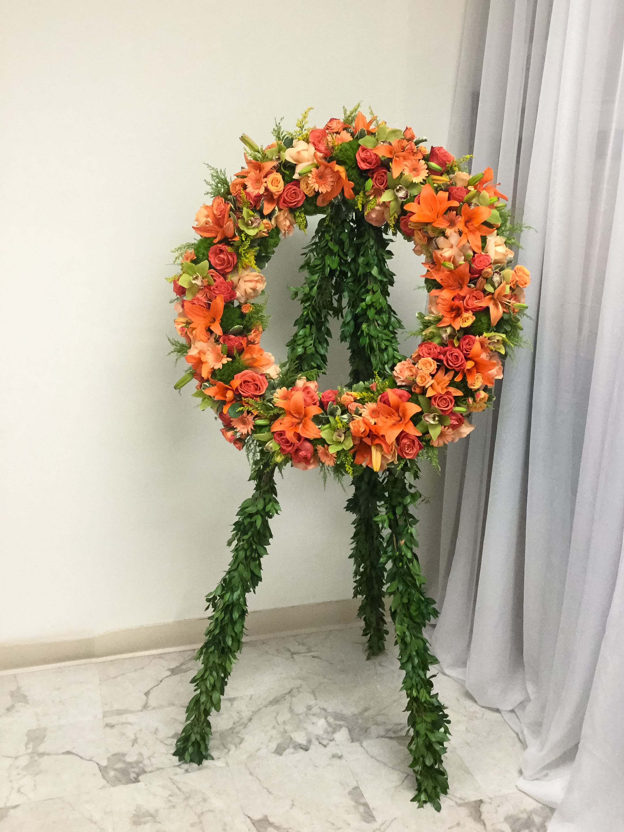 Large floral wreath on a stand with orange and pink blooms