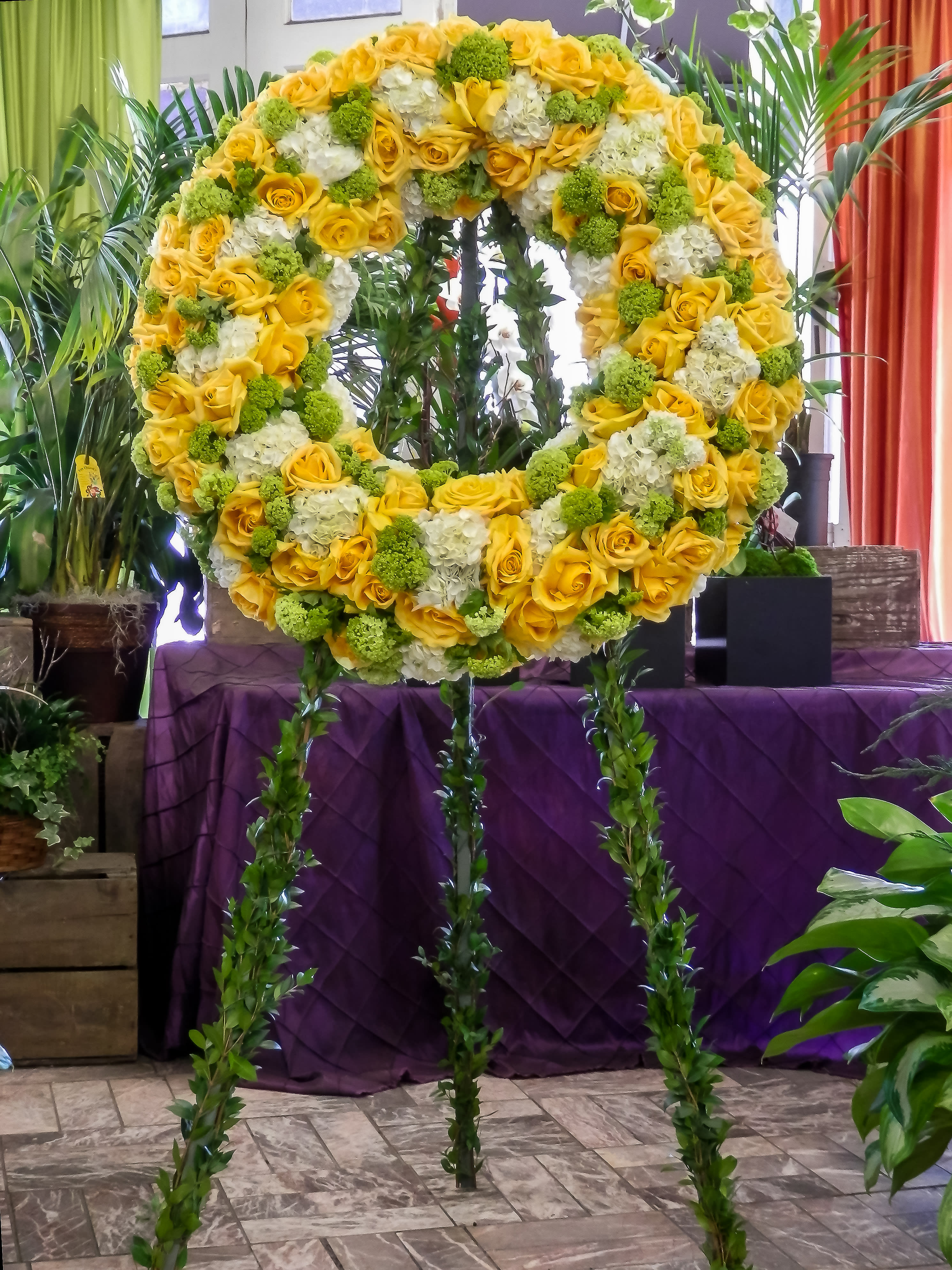 Large yellow and white floral wreath on a stand