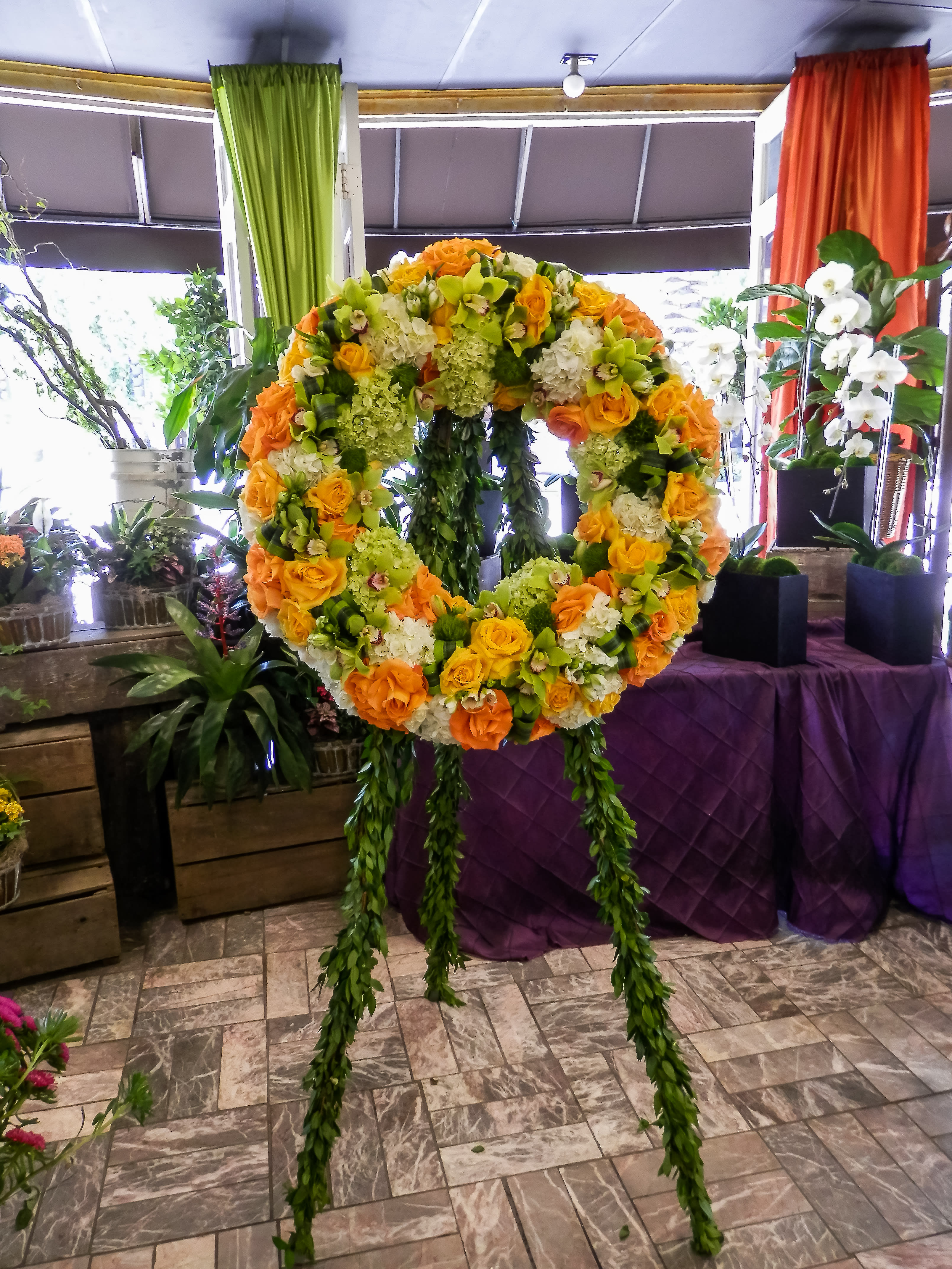 Large floral wreath on a stand with orange, yellow, and white blooms