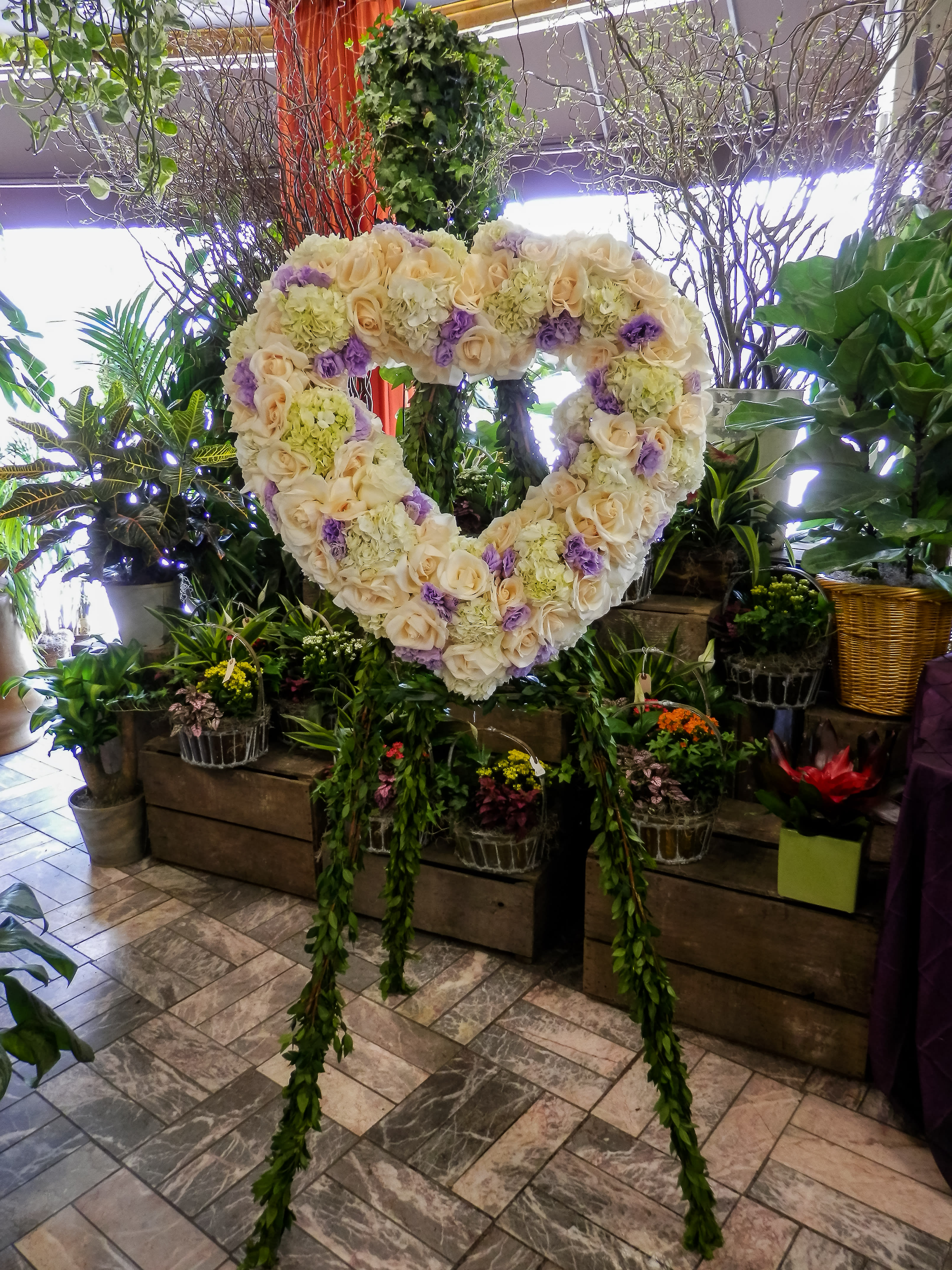 Heart-shaped floral wreath of cream and lavender blooms on a stand