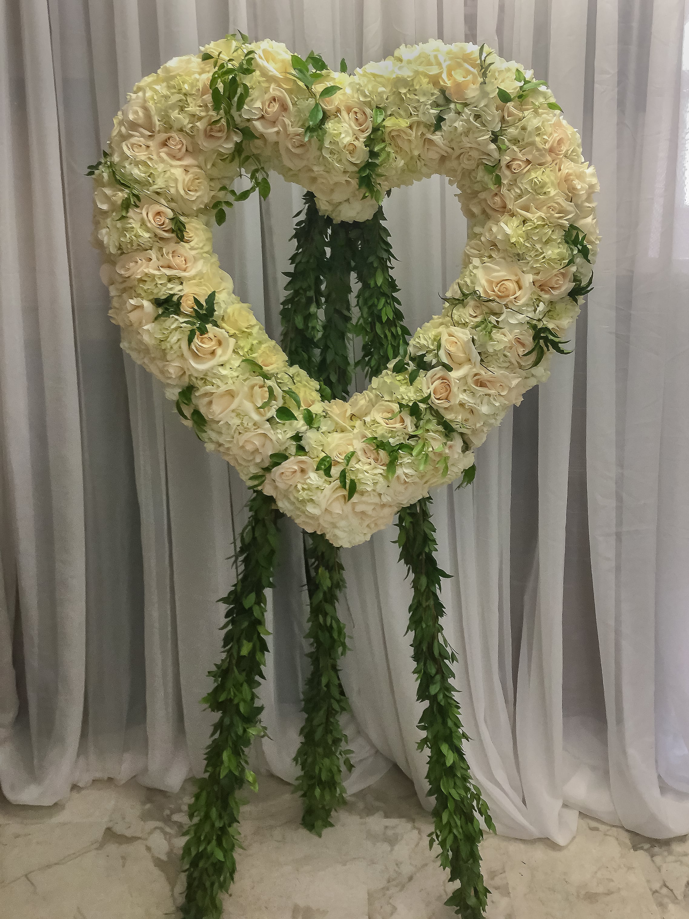 Heart-shaped floral standing arrangement with cream roses and hydrangeas