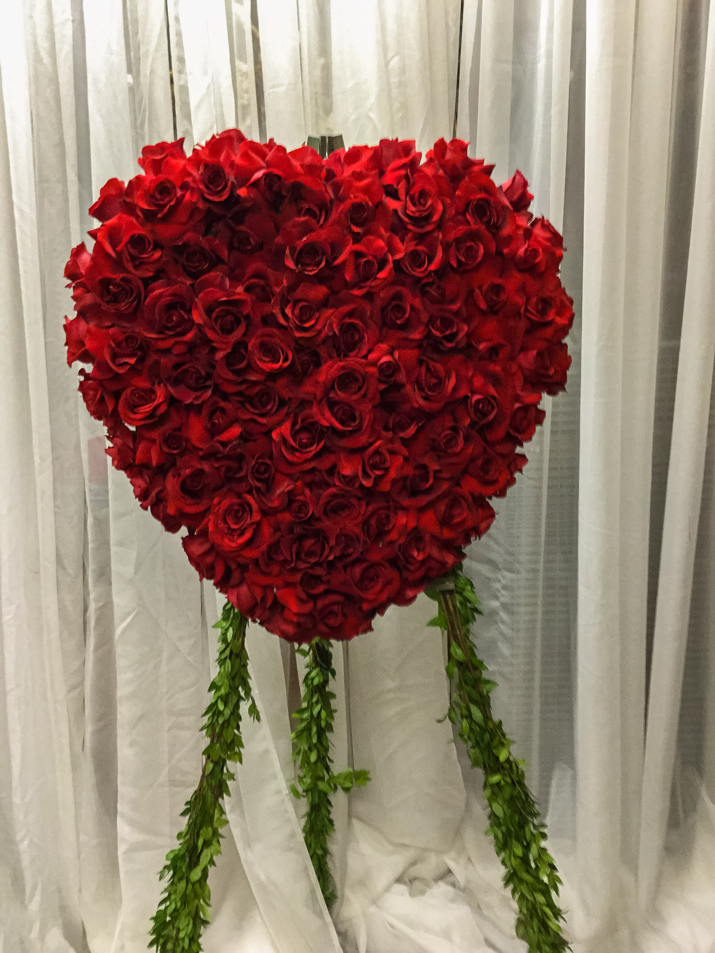 Heart-shaped red rose arrangement with hanging greenery