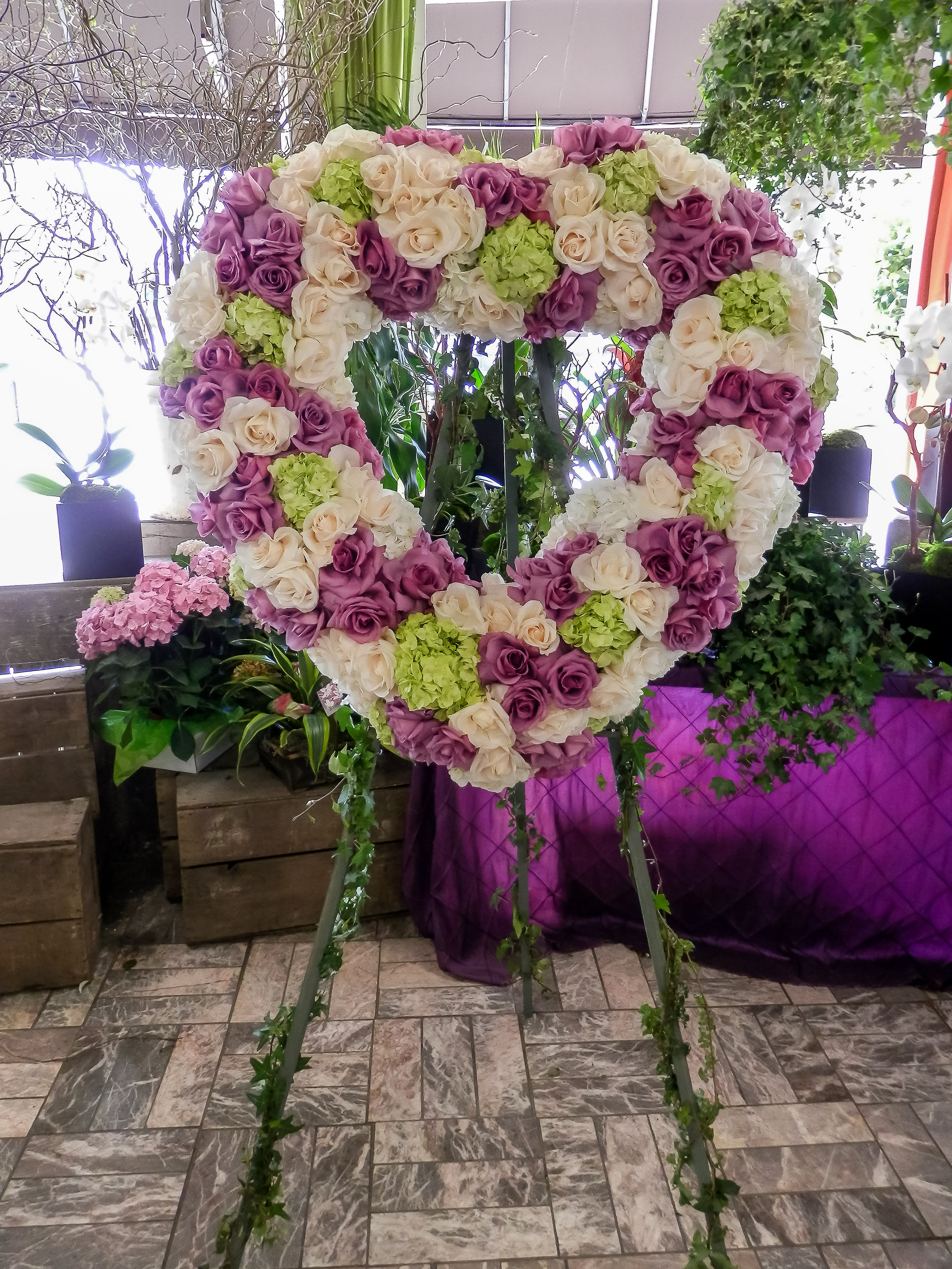 Heart-shaped floral display of pink, cream, and green roses on a stand
