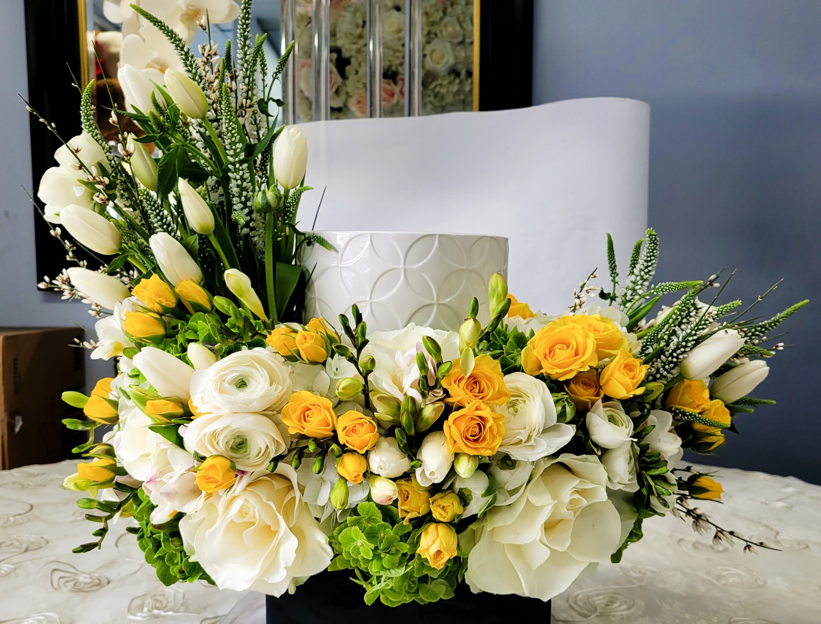 White and yellow floral arrangement with roses and tulips in a white vase