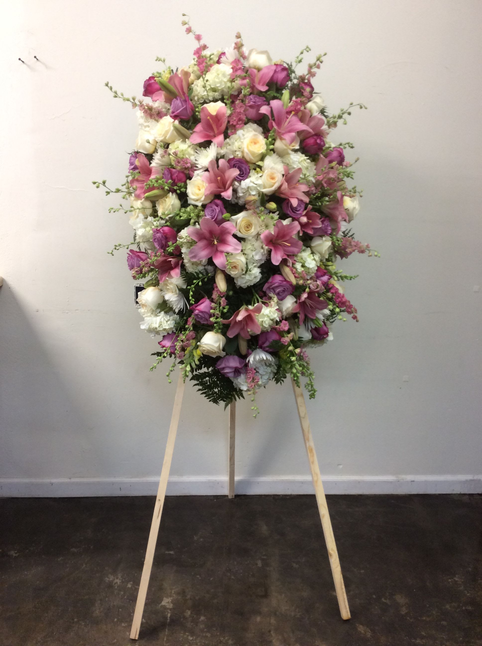Large pink and white funeral spray on a wooden easel