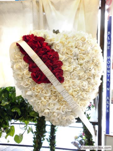Heart-shaped rose wreath with red and white roses and a diagonal ribbon