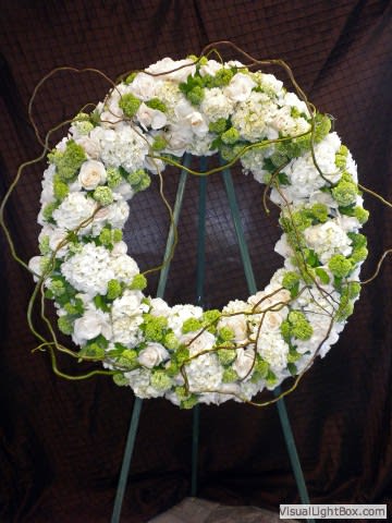 White and green floral wreath on a stand