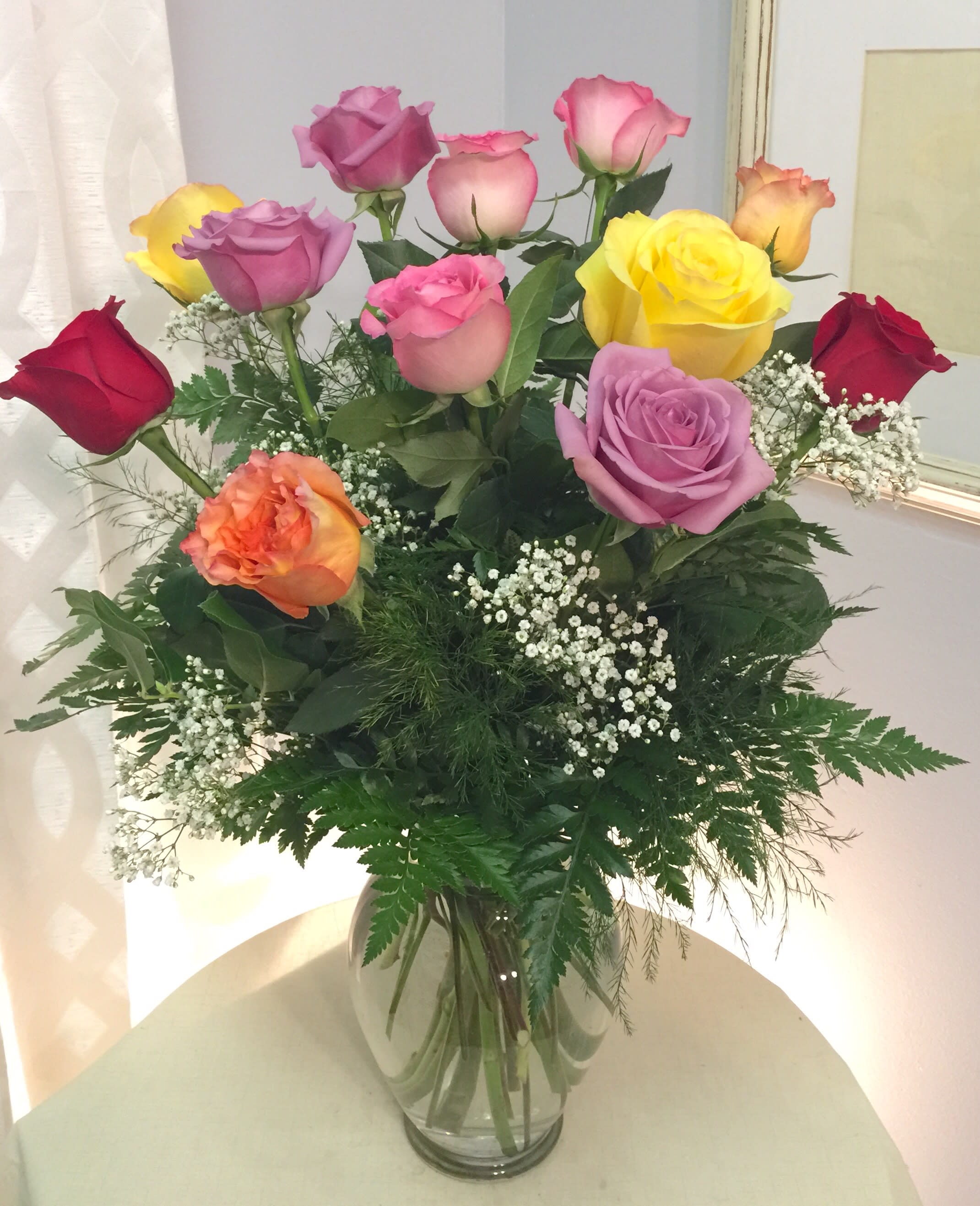 Mixed roses in a clear glass vase with baby's breath