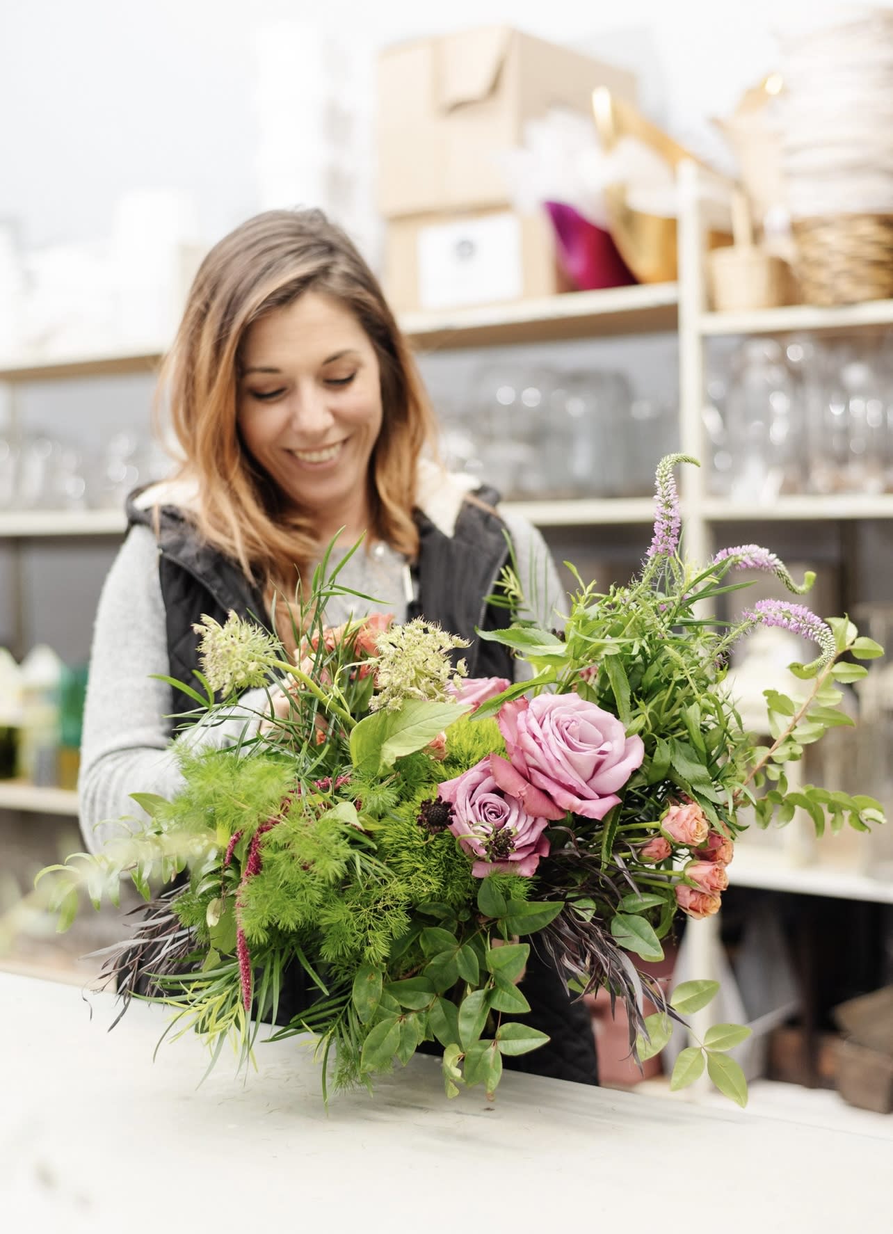 Woman holding a large bouquet of pink roses and greenery