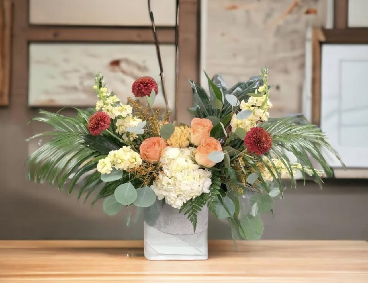 Mixed floral arrangement in a white square vase with peach and cream blooms