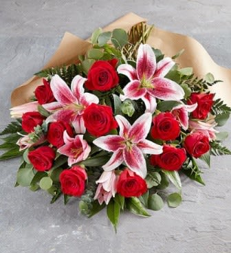 Bouquet of red roses and pink lilies wrapped in brown paper