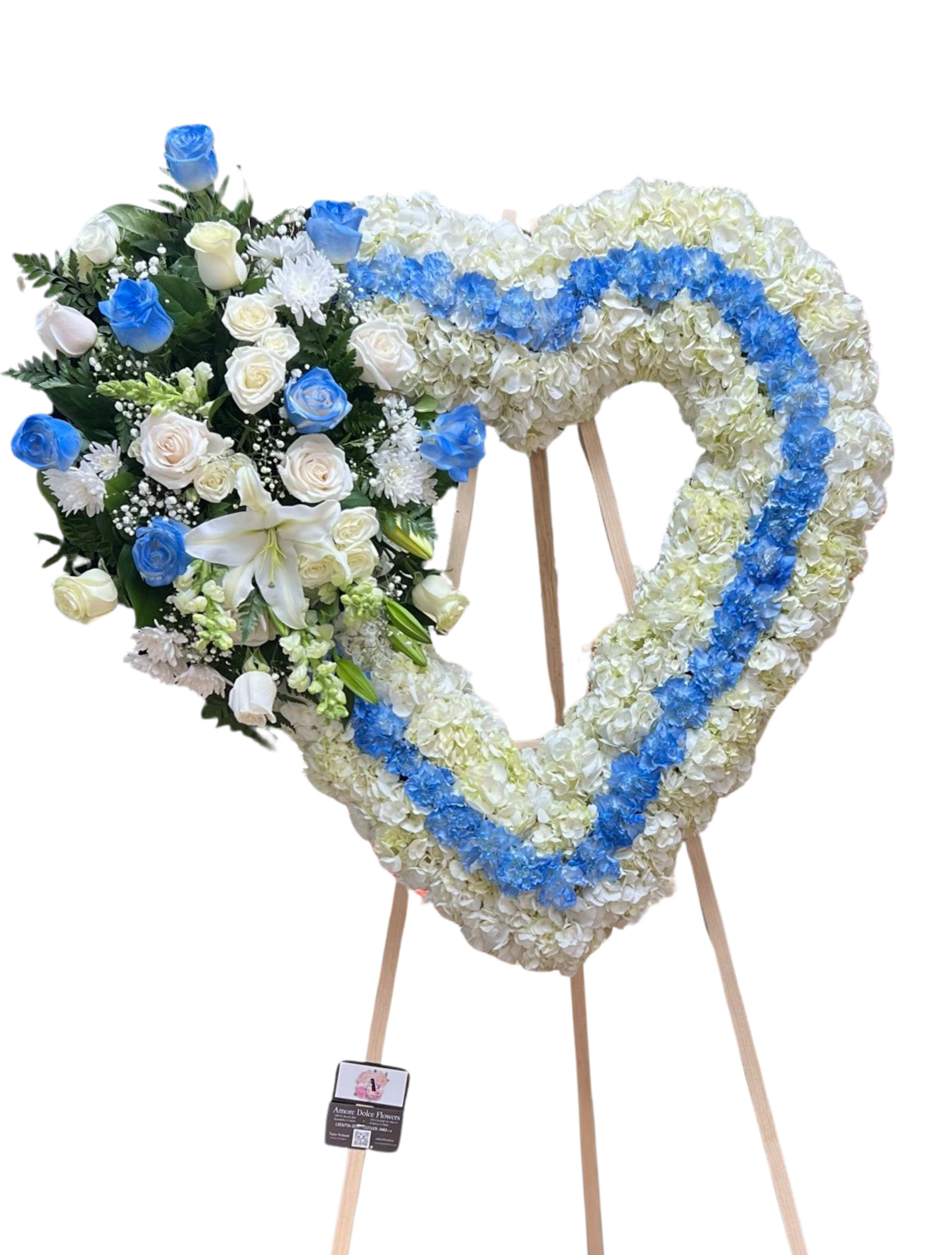 Heart-shaped floral wreath on an easel with blue and white flowers