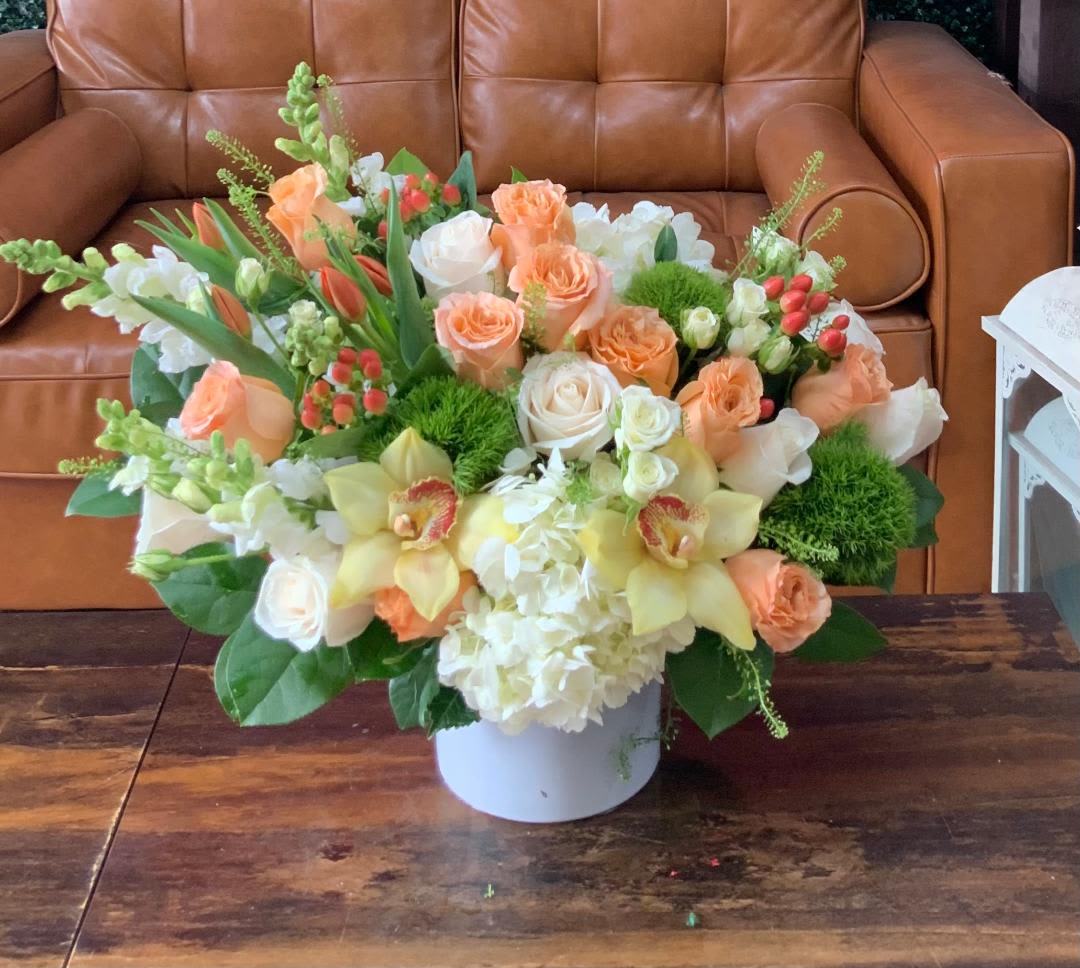 Peach and white floral arrangement in a white vase on a table