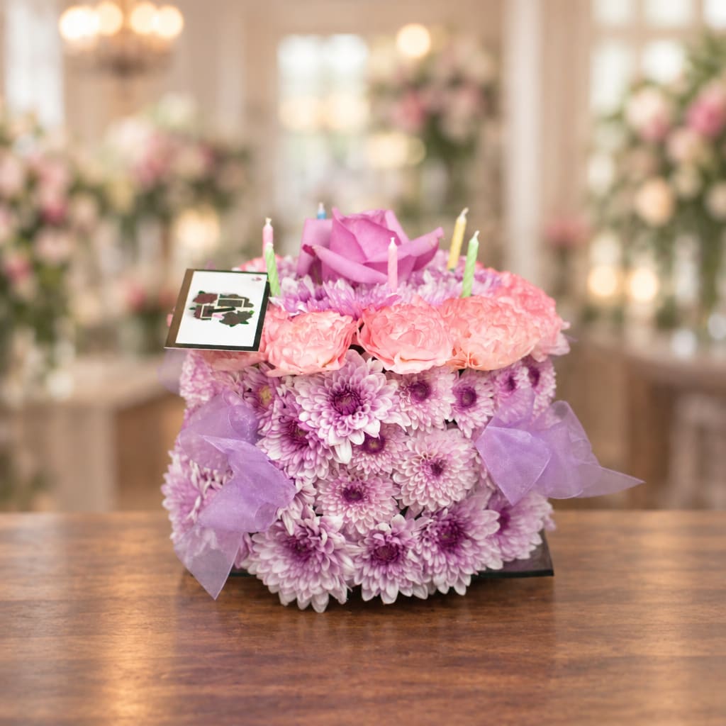 Purple and pink floral arrangement with candles on a table